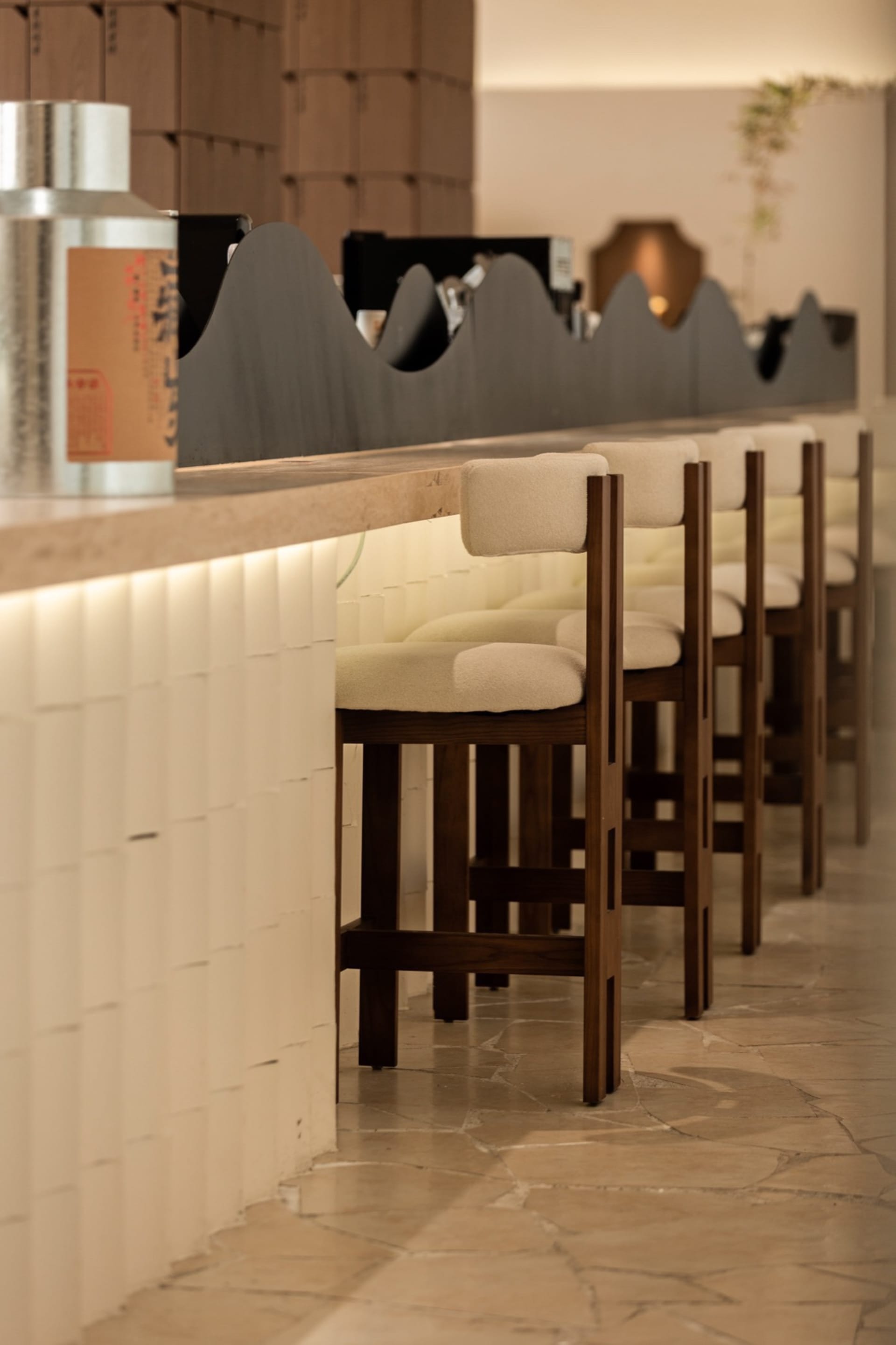 Warm and inviting bar area with wooden stools and tables, black countertop, and multiple chairs for socializing