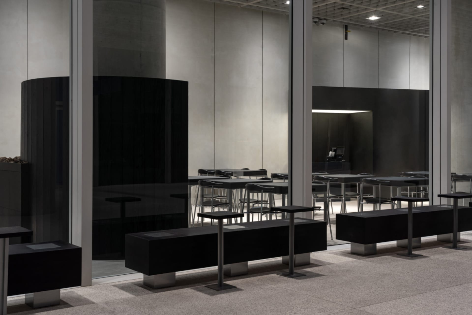 Empty modern restaurant with metal tables and chairs, natural light from a large window, and a welcoming atmosphere