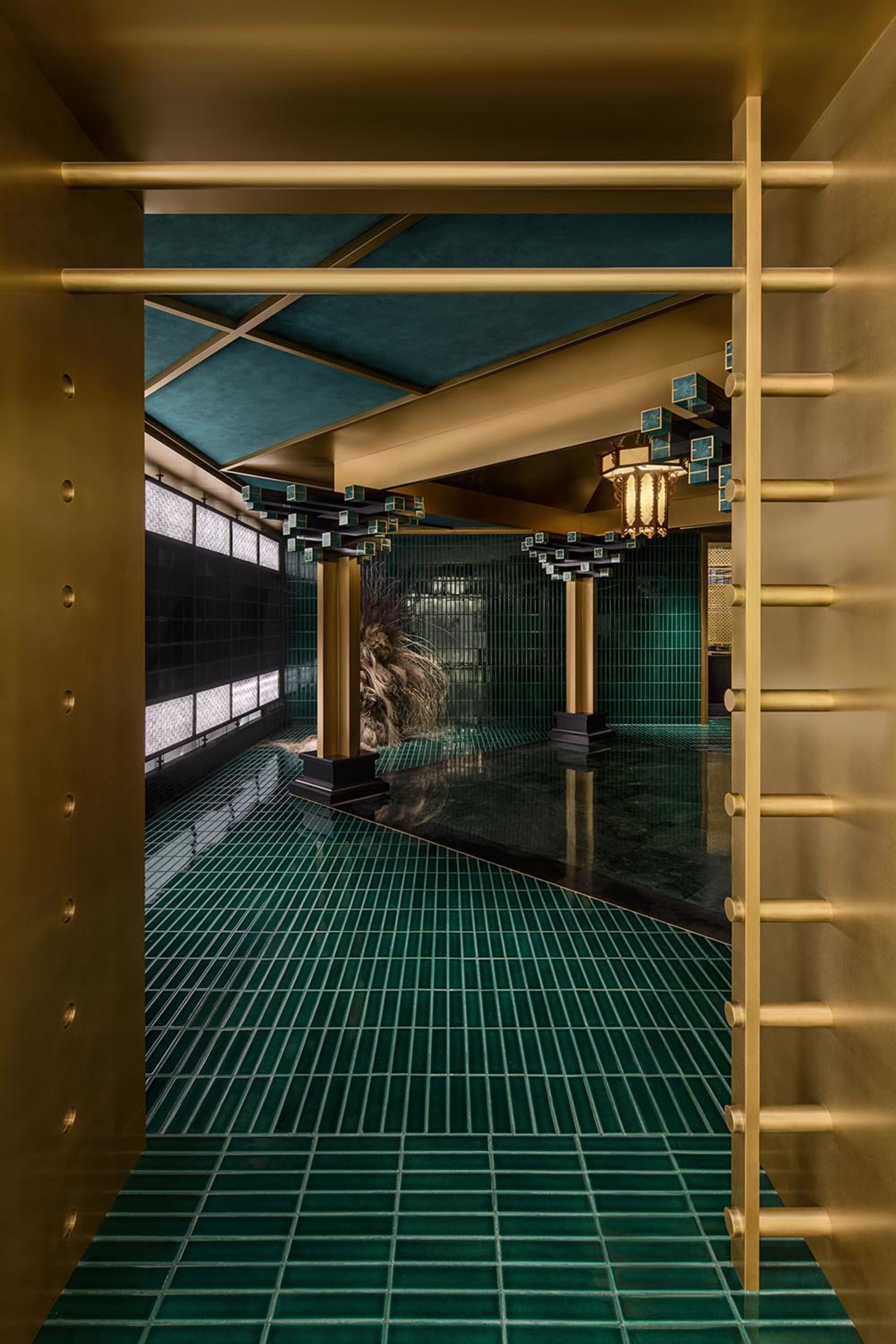 Luxurious bathroom with green tiles, two large columns, and well-lit interior