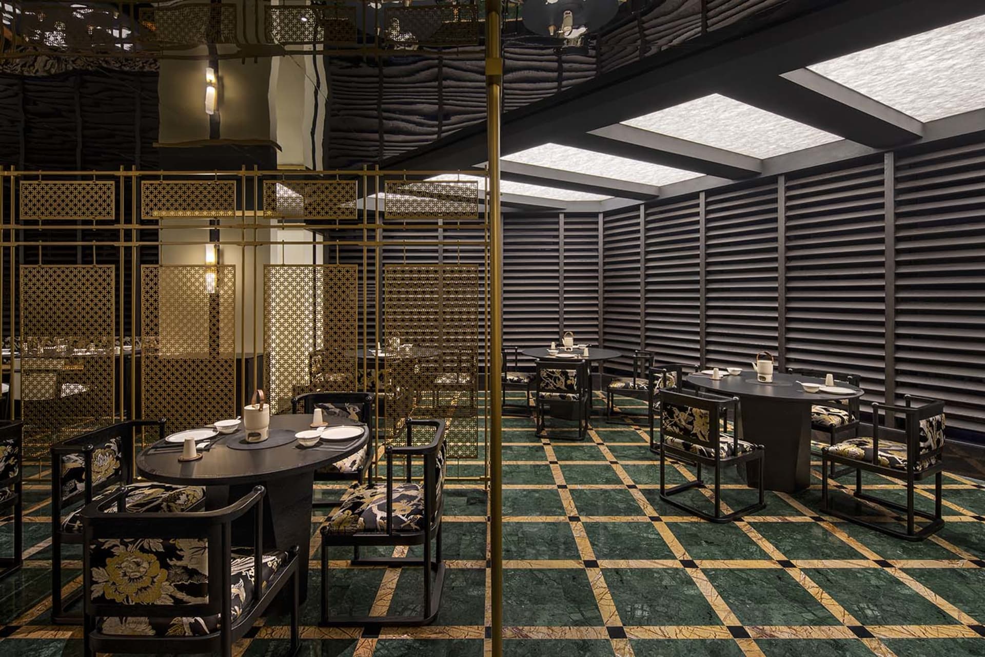 Dining area with multiple tables and chairs, green tile flooring, and warm lighting creating an elegant and inviting atmosphere