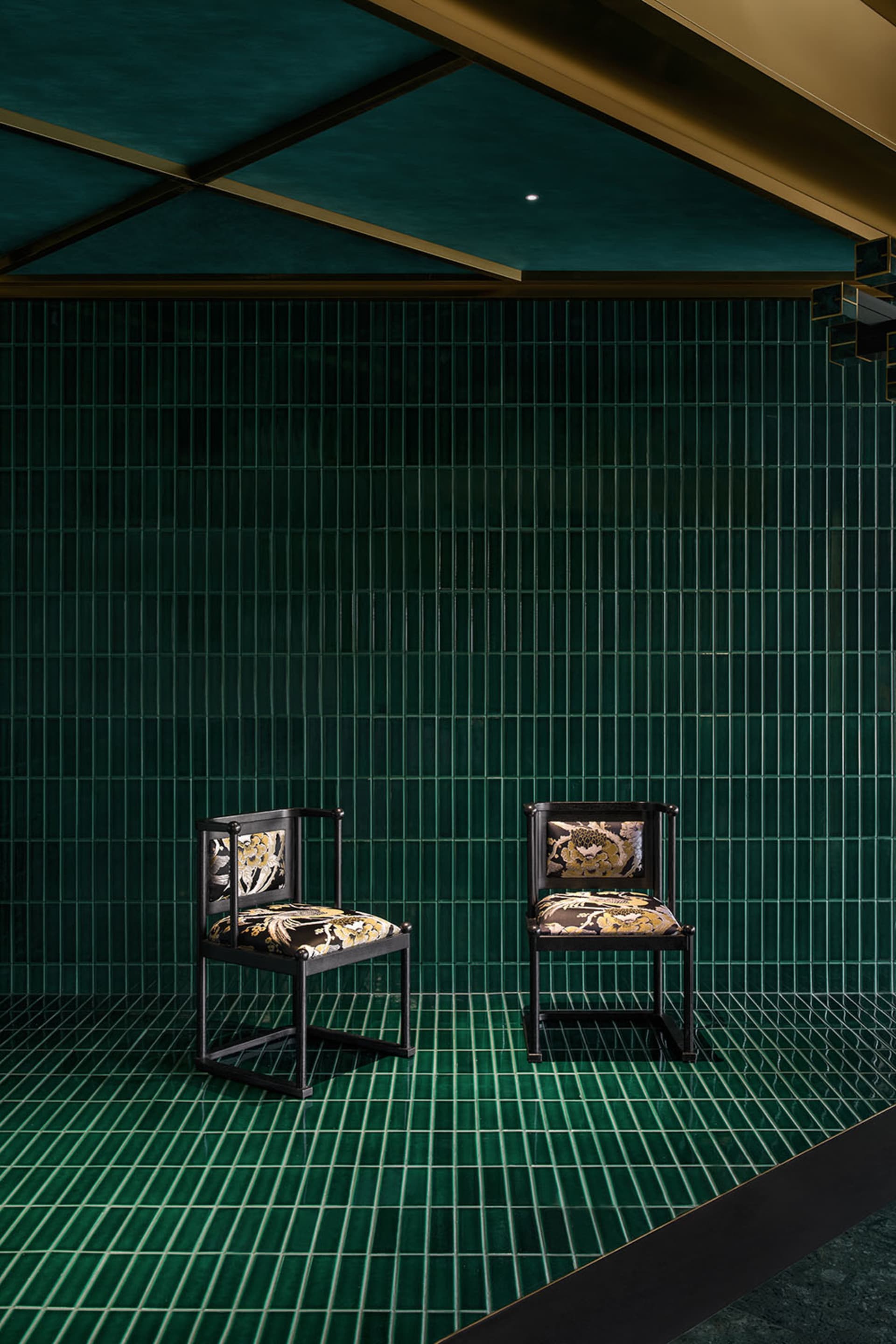 Two chairs placed at an angle in front of a green wall, creating a sense of depth and balance in a calm and inviting space