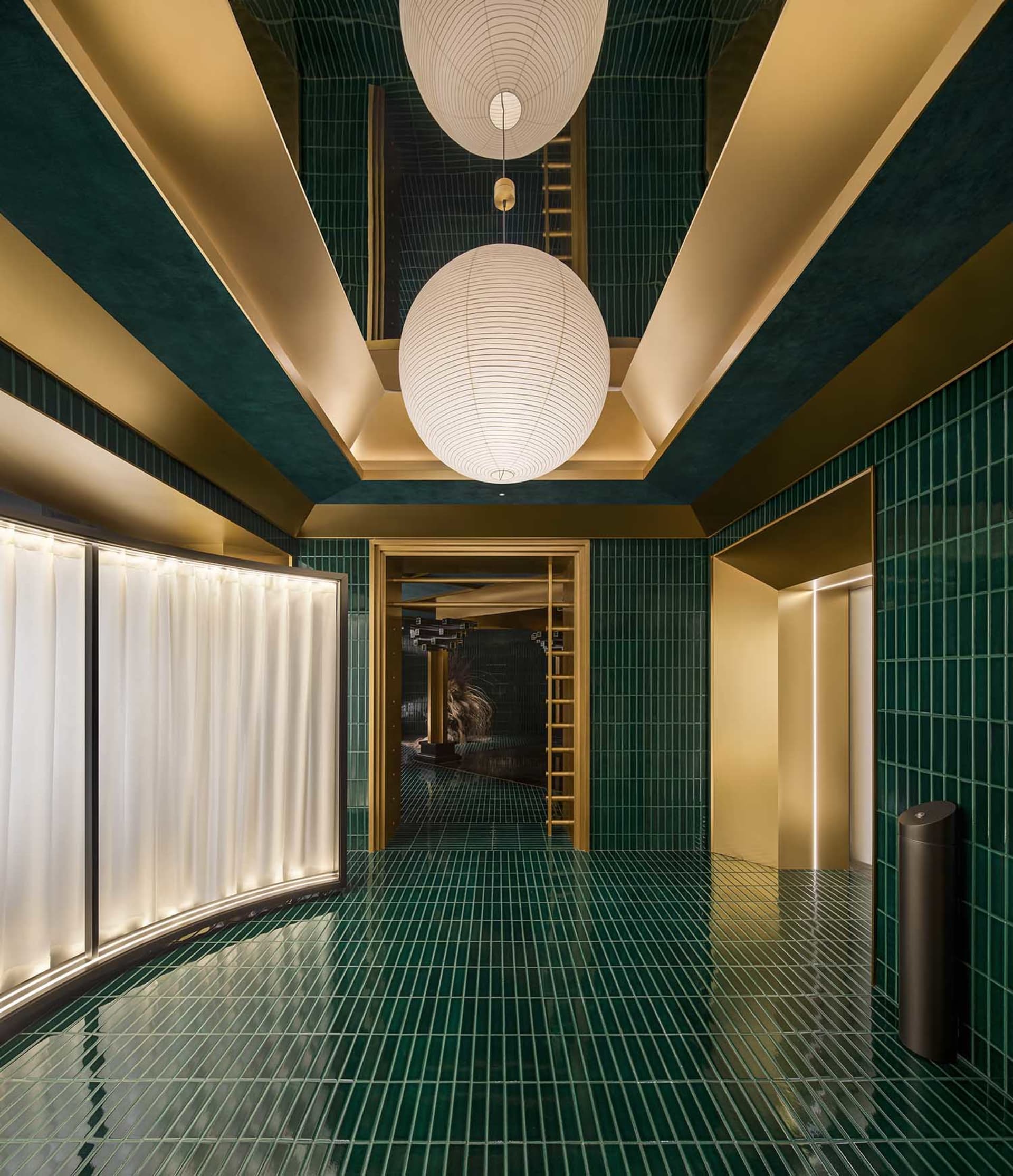 Ornate hallway with green walls, gold accents, a spiral staircase, and three white globes suspended from the ceiling