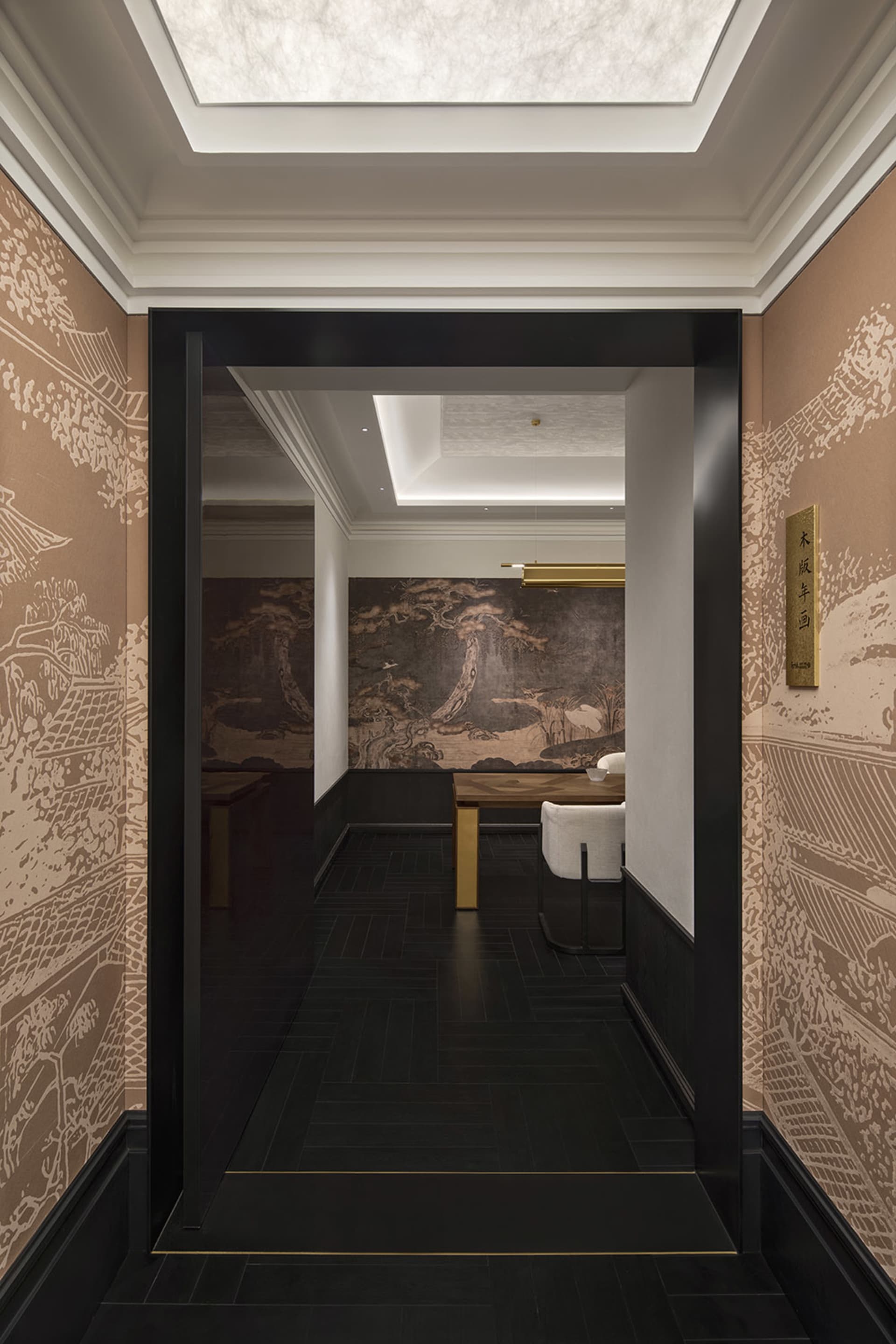 Asian-inspired living room with a wooden table, chairs, and couch, adorned with intricate artwork and a black doorway leading to another room