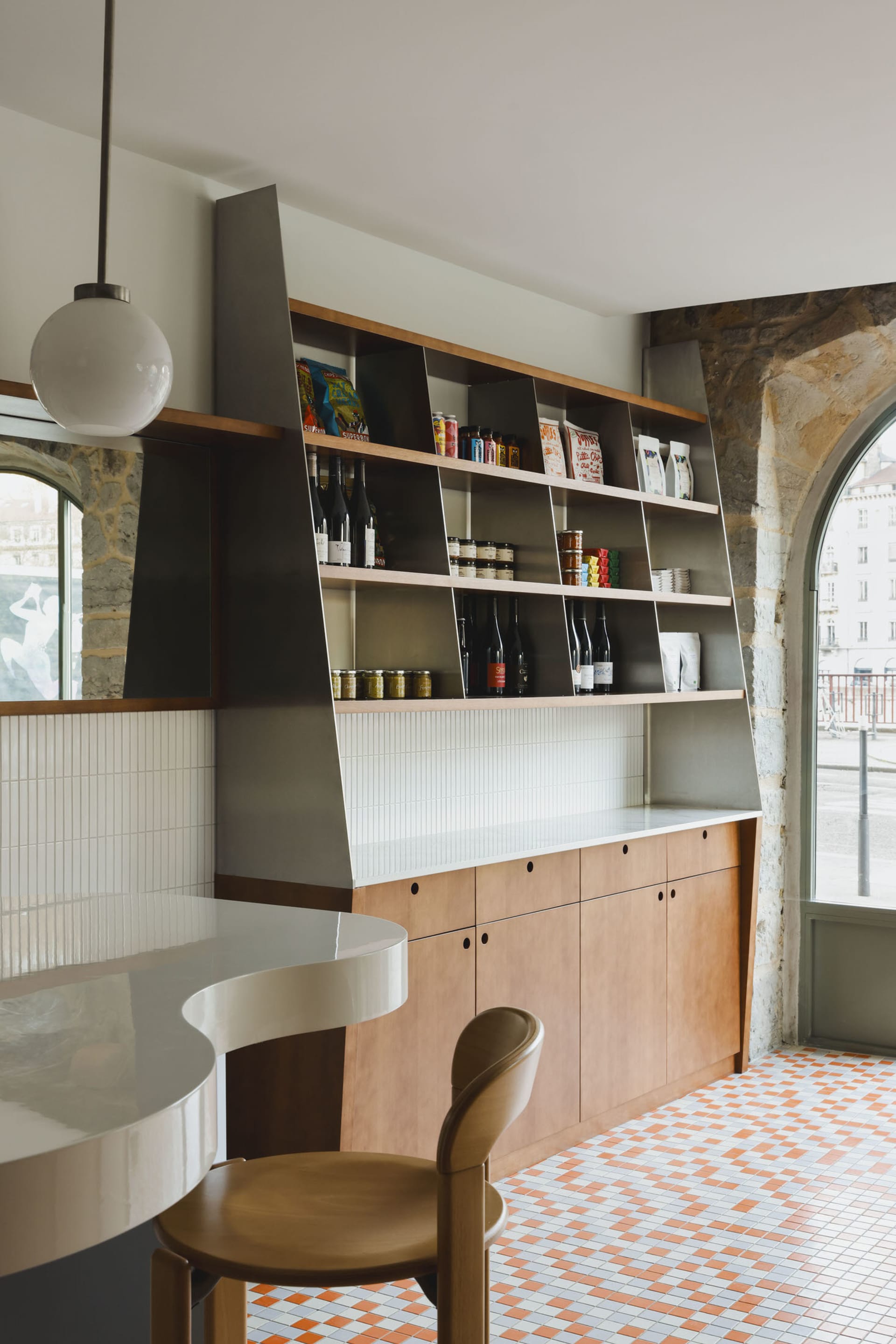 A cozy kitchen with a countertop island, sink, and wine rack, surrounded by bottles and books, with a focus on functionality and organization