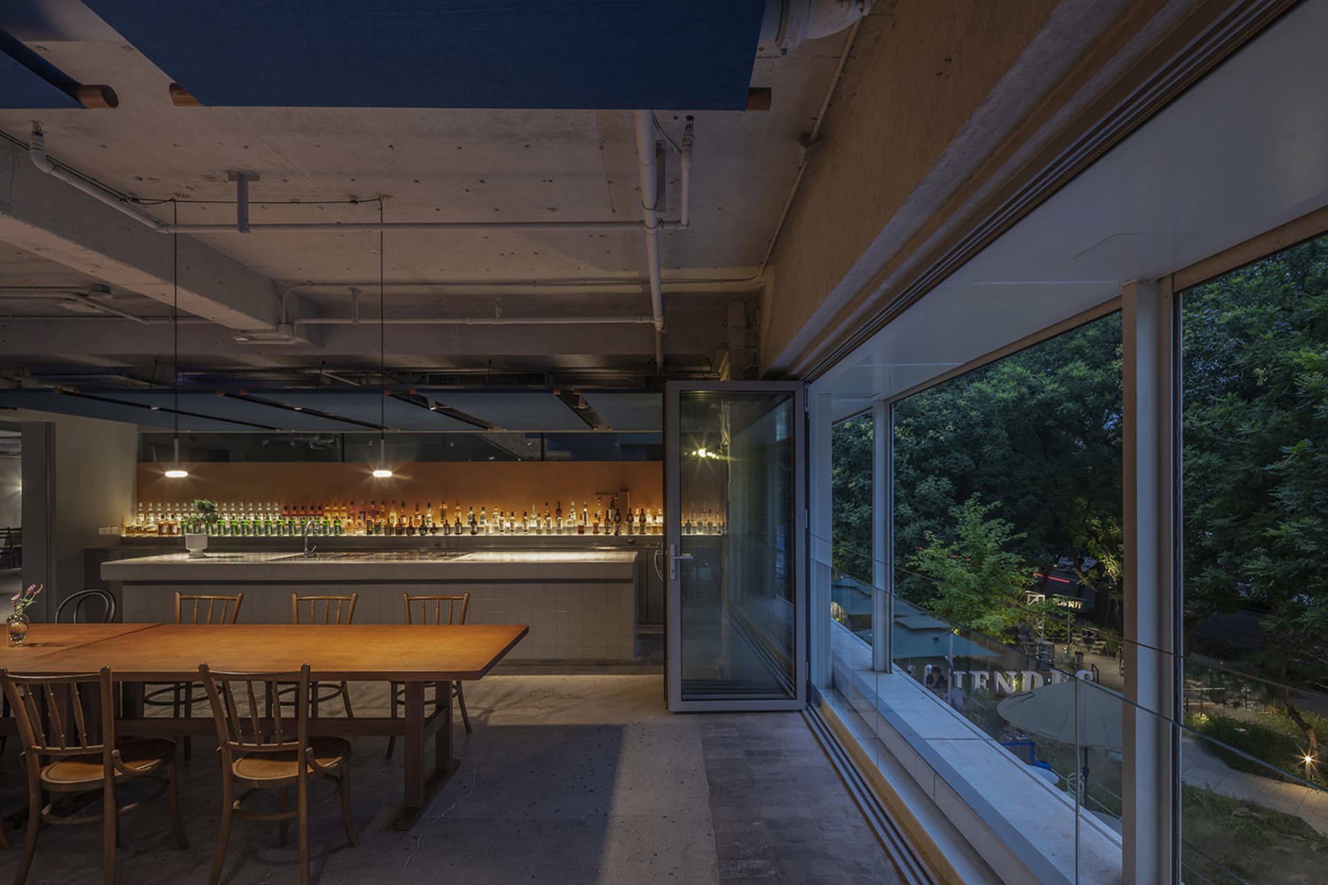 A cozy wine bar with a dining table surrounded by chairs, bottles, and cups, creating an inviting atmosphere for socializing and enjoying food and drinks