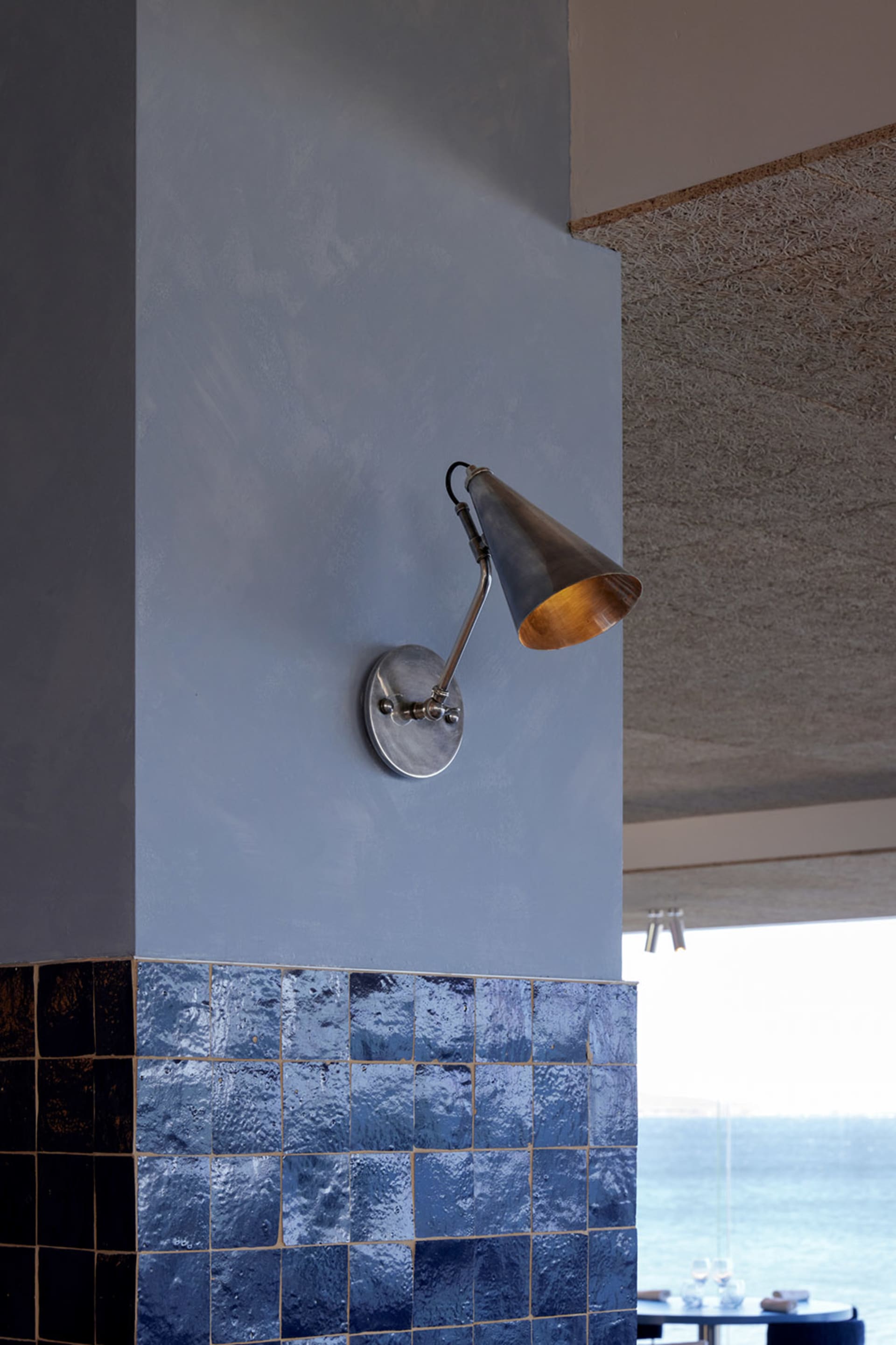 A modern interior space with a metal lamp on a tile wall, giving a clean and well-lit atmosphere