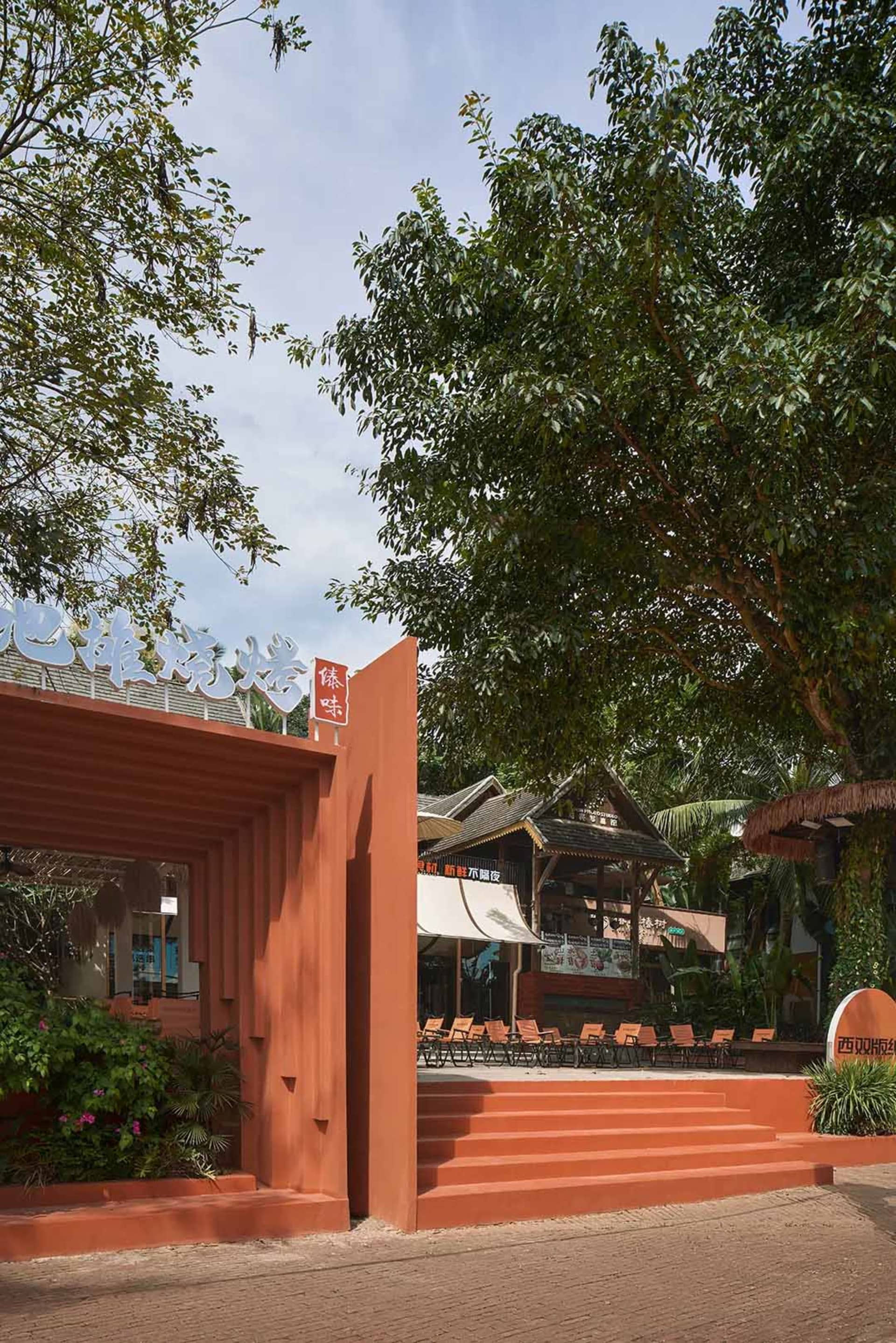 A restaurant with an orange building and a red door, featuring outdoor seating with chairs in various positions, creating a welcoming atmosphere for visitors