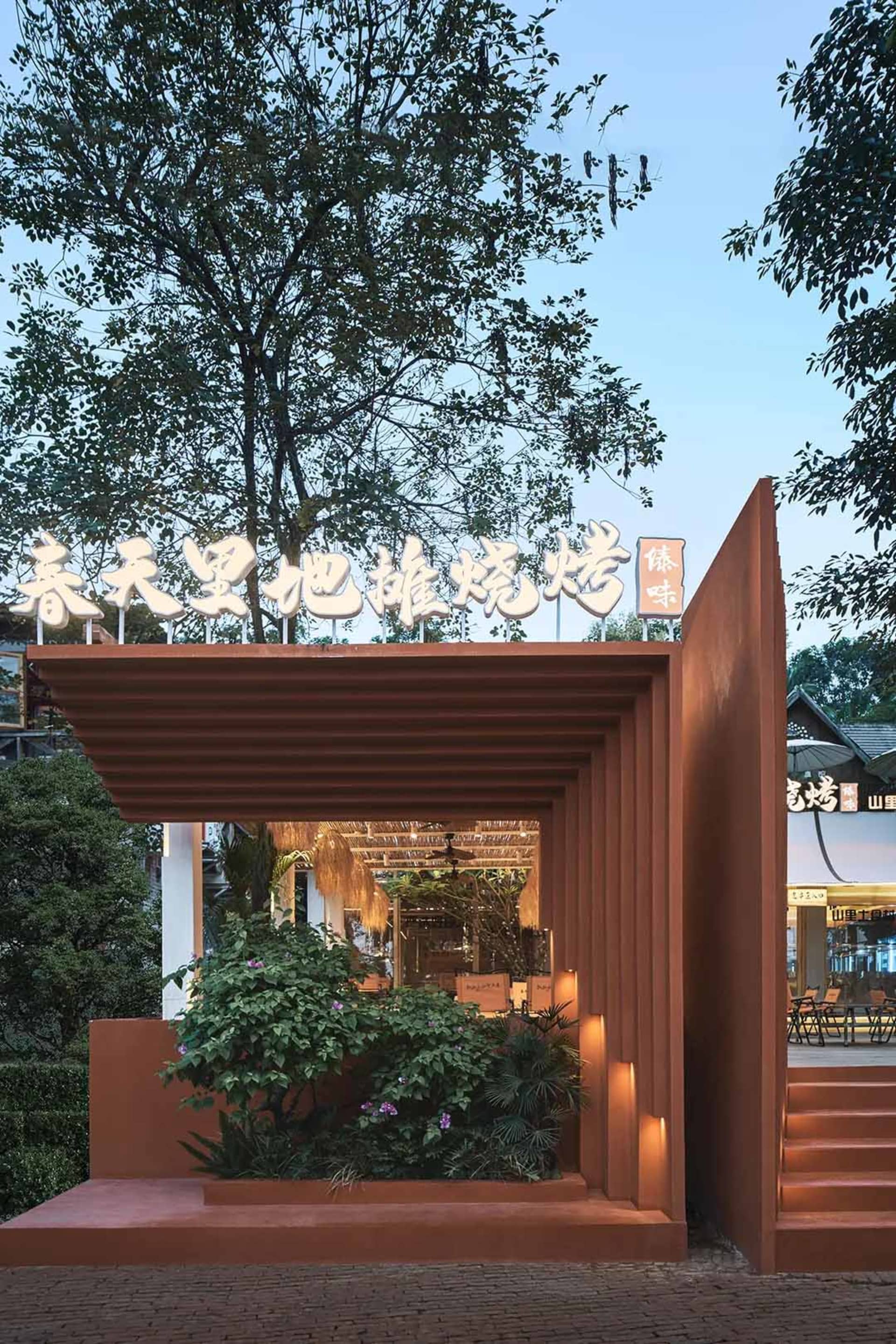 Cozy Asian restaurant with a unique tree trunk structure, red roof, and well-lit interior with dining tables and chairs