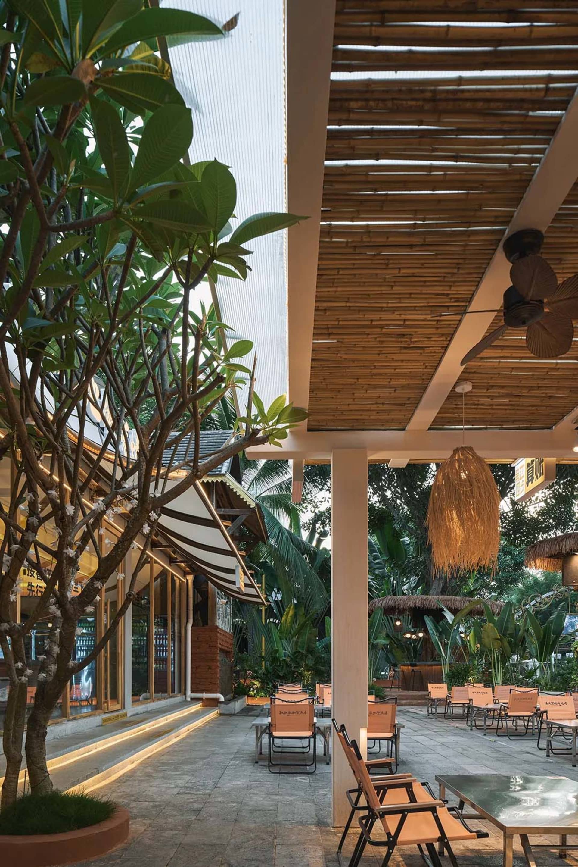 Outdoor dining area with a thatched roof, palm trees, and comfortable seating with cushions