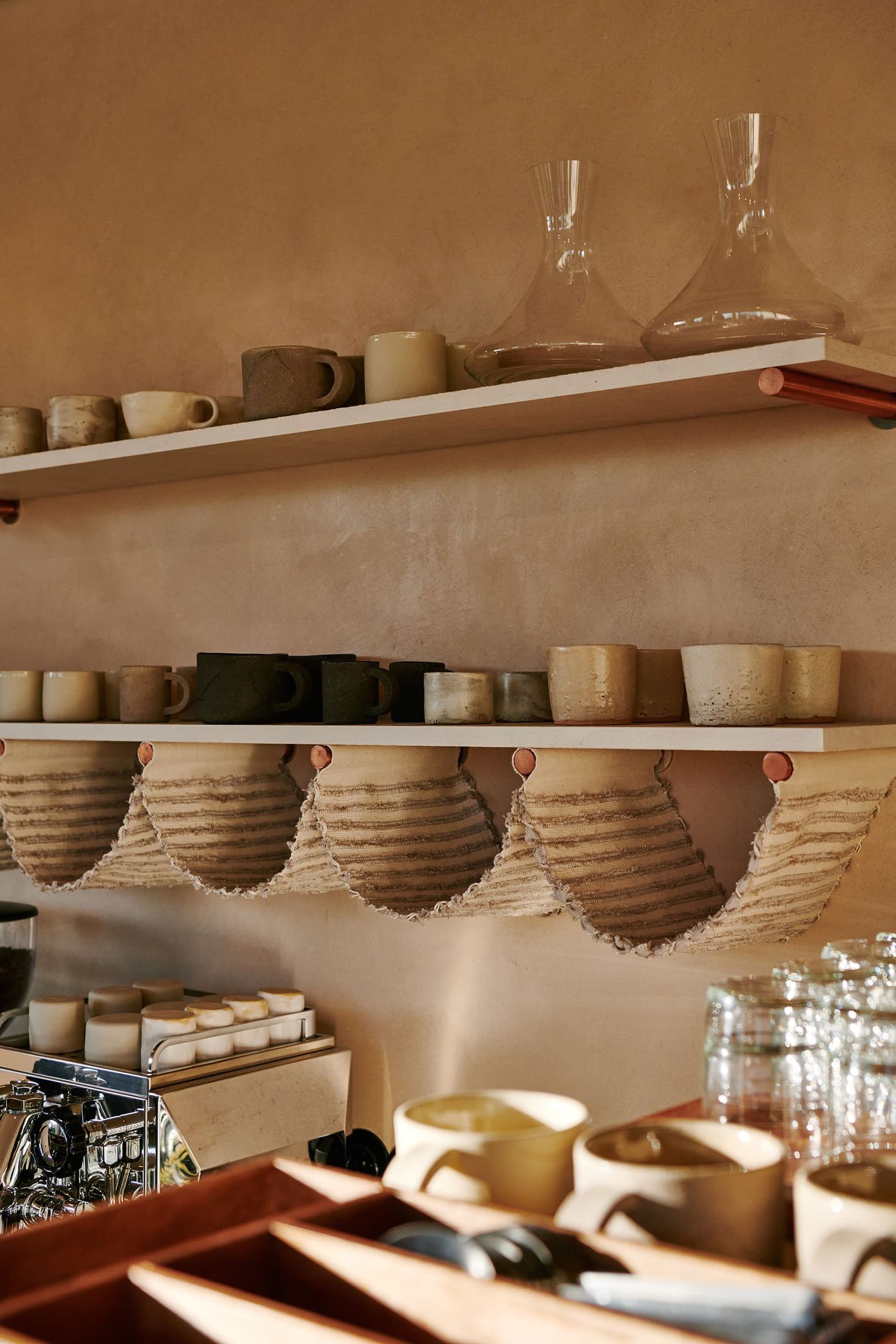 A kitchen with a shelf displaying various cups and bowls in an organized and visually appealing manner, creating a functional and inviting atmosphere