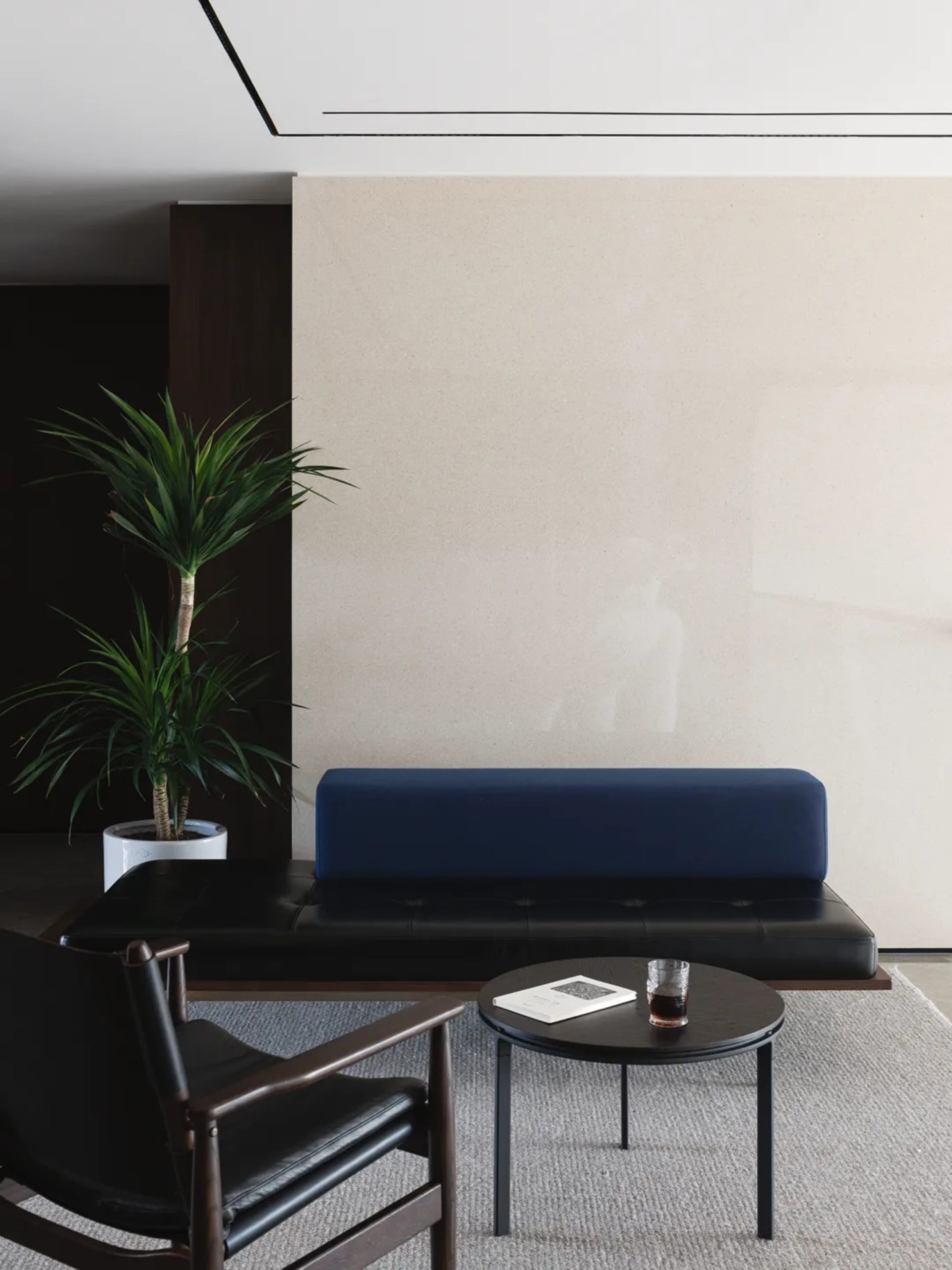 Cozy modern living space with a stone wall, a couch, chair, and dining table, featuring potted plants and a vase