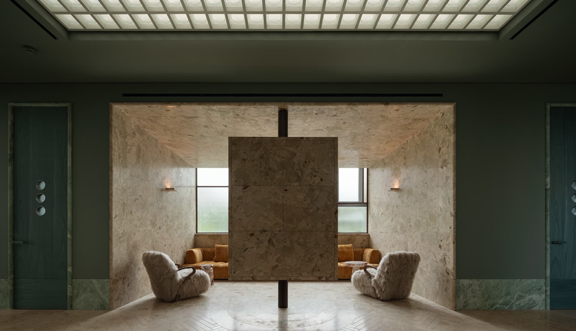 Modern living space with a large stone wall, two chairs, and a couch, featuring a minimalist and warm atmosphere