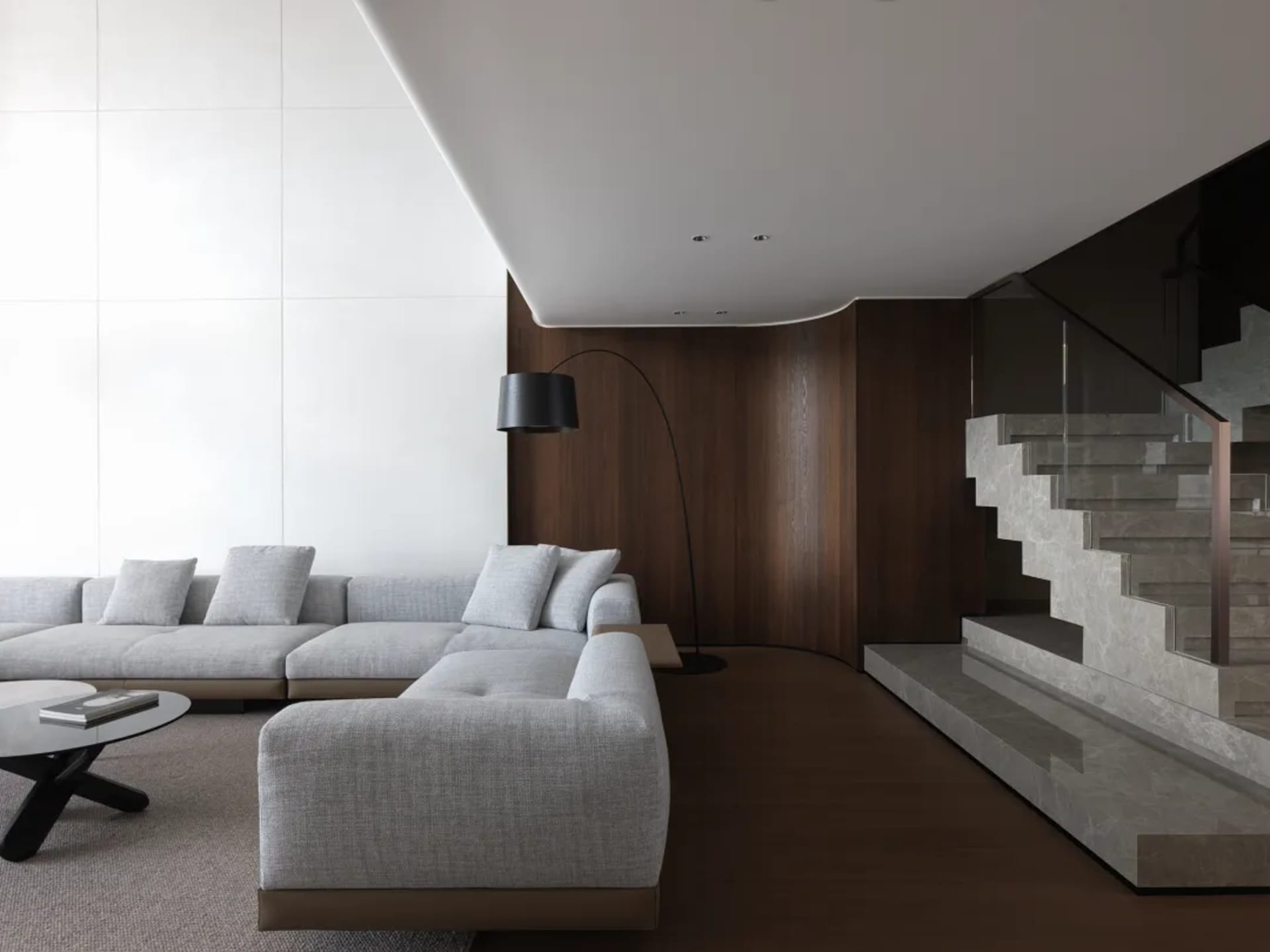 Open living area with a large couch, a chair, and a carpeted floor, featuring a warm and inviting atmosphere with wooden accents and good lighting
