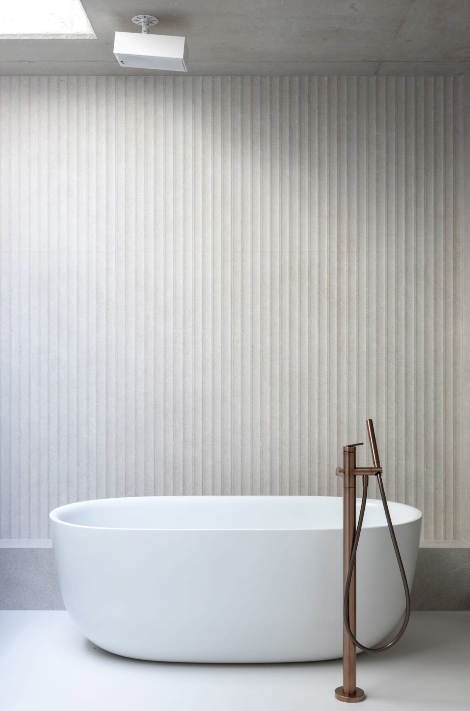 A clean and well-maintained bathroom with a white bathtub and striped walls