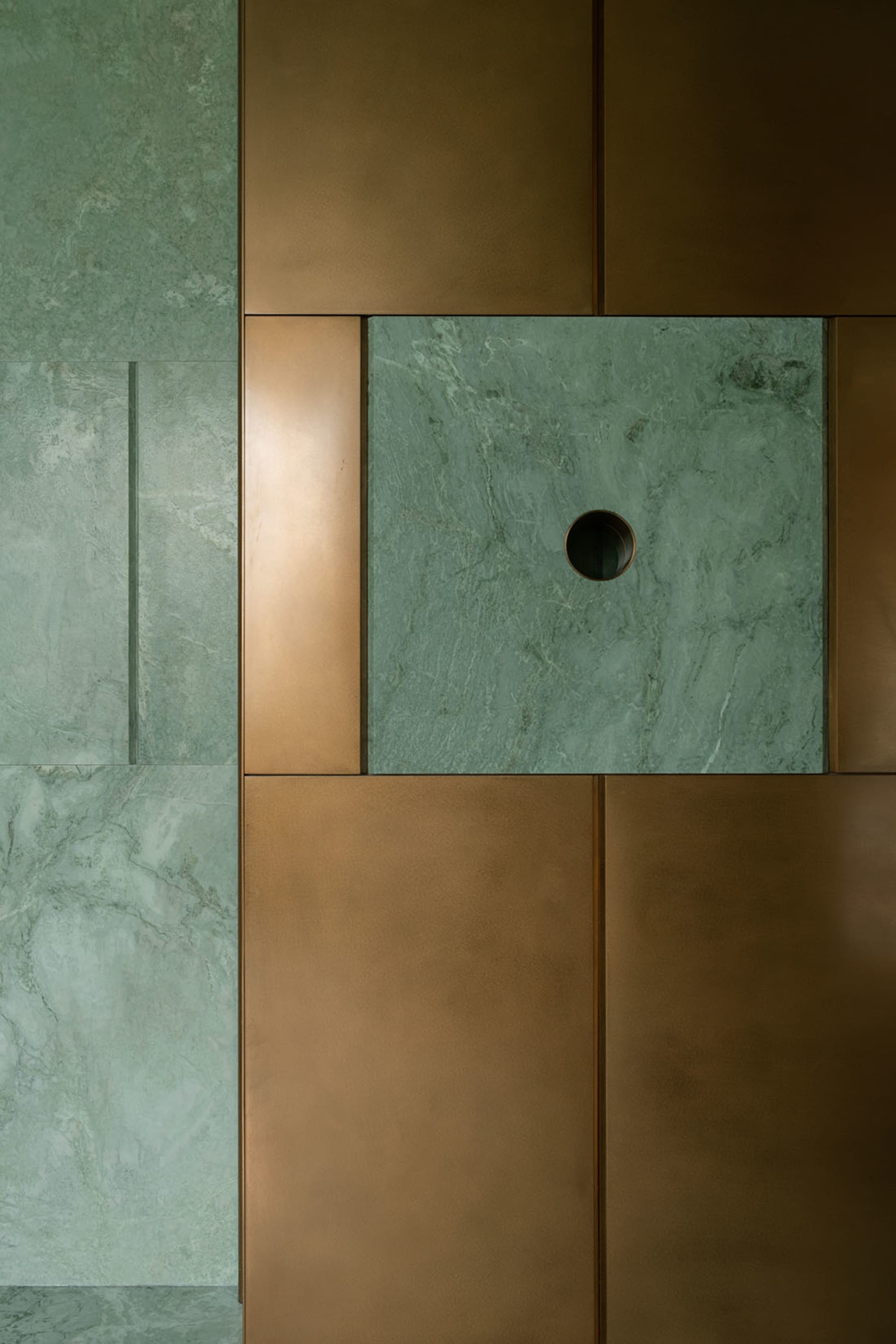 A luxurious interior space with a green marble wall, gold metal frame, and high-end aesthetic
