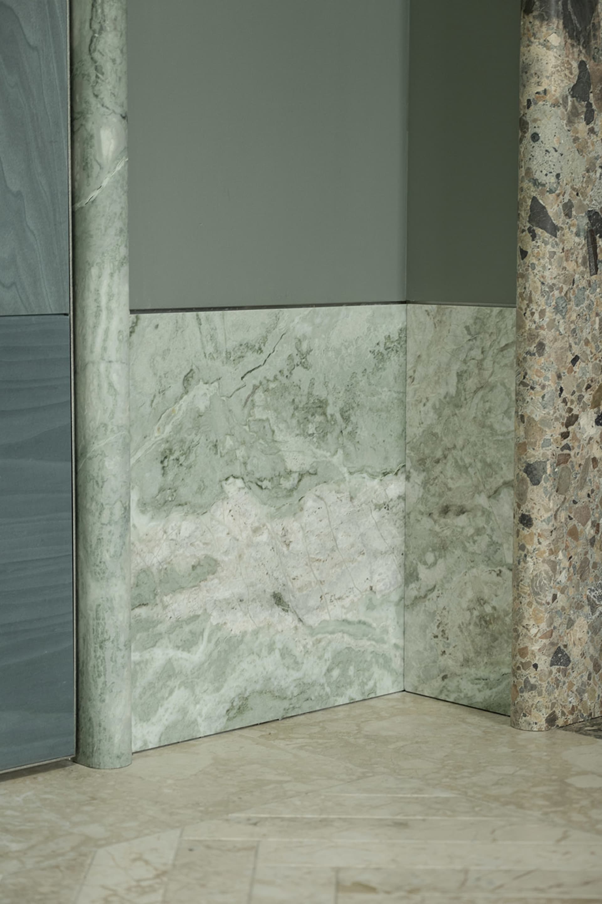 A modern bathroom with a marble wall and green marble countertop, featuring a sophisticated and elegant design with warm lighting