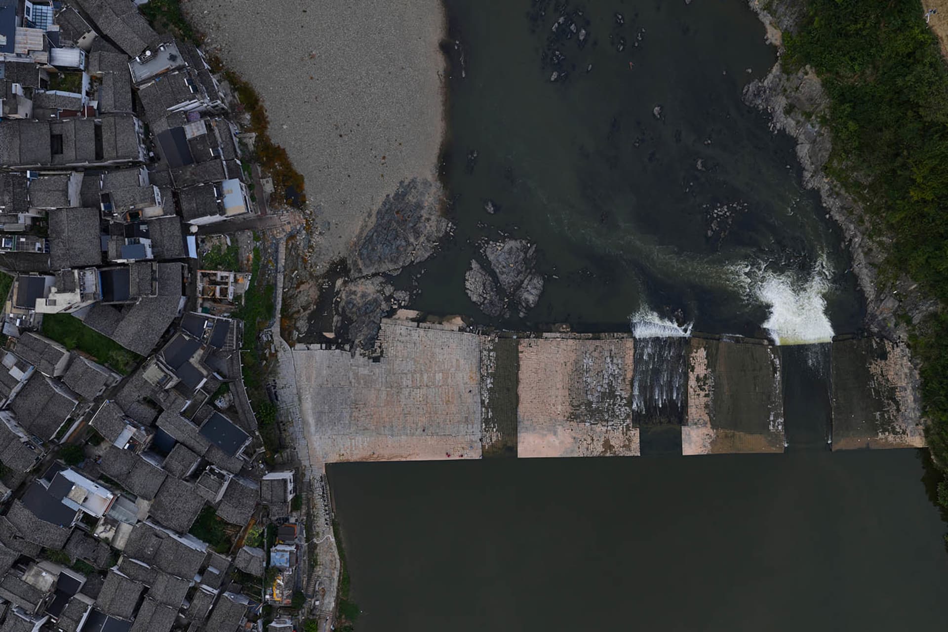 A cityscape with a dam constructed from concrete, surrounded by buildings and a body of water