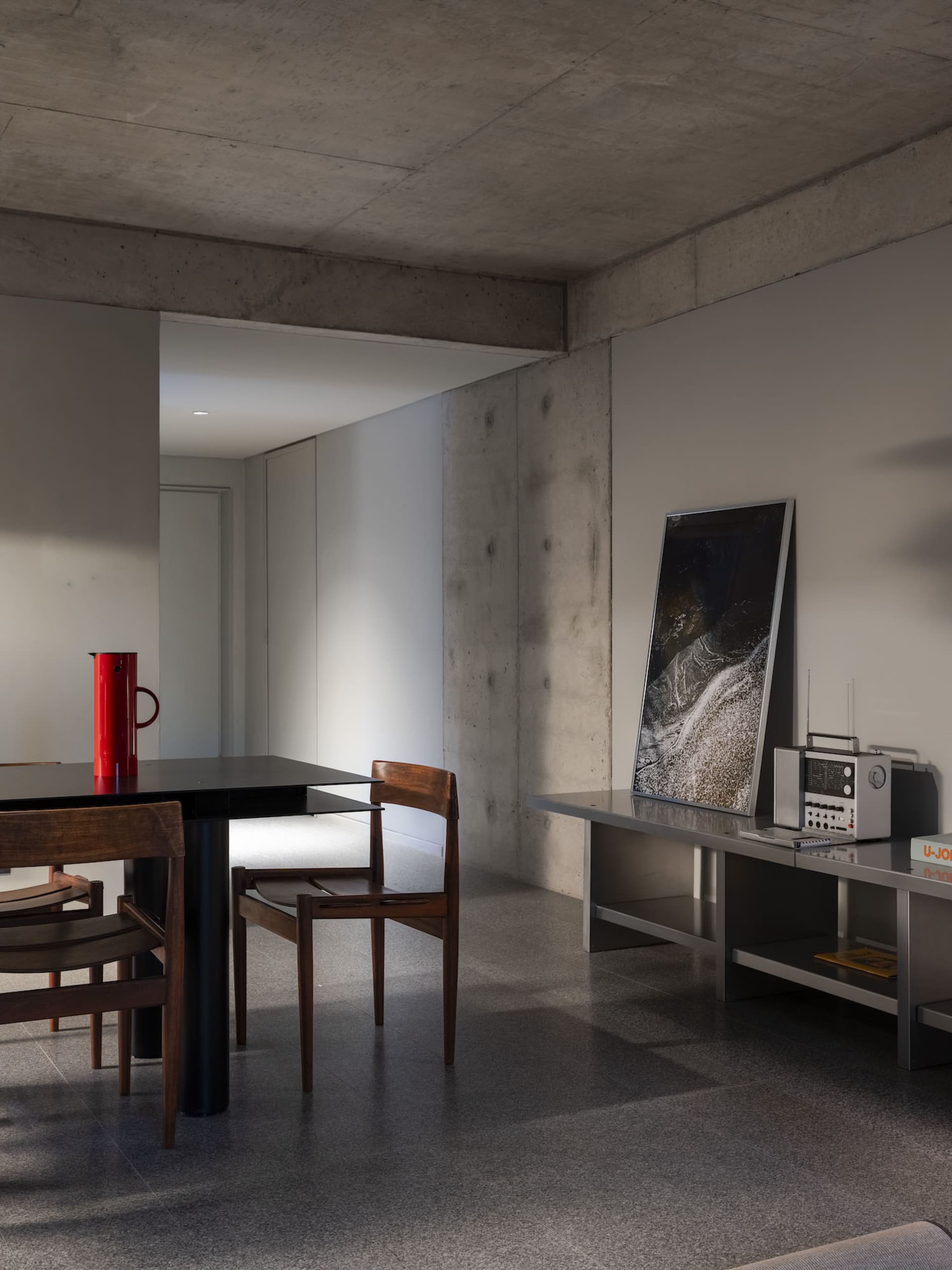 A well-lit, modern room with a dining table and chairs, surrounded by clean lines and minimalistic decoration