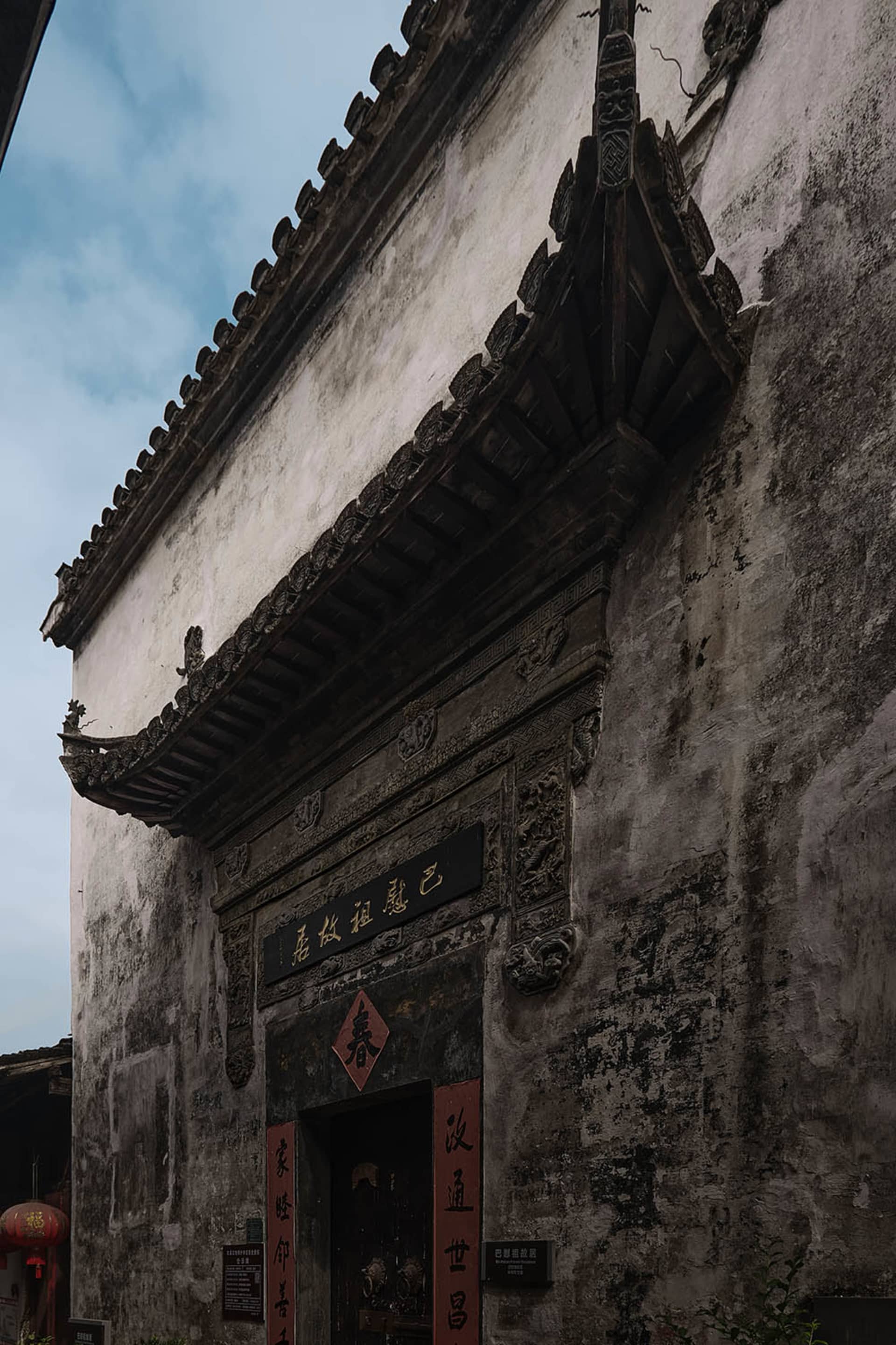A traditional Chinese building with a red doorway and black sign, featuring a stone exterior and a sense of history and cultural significance
