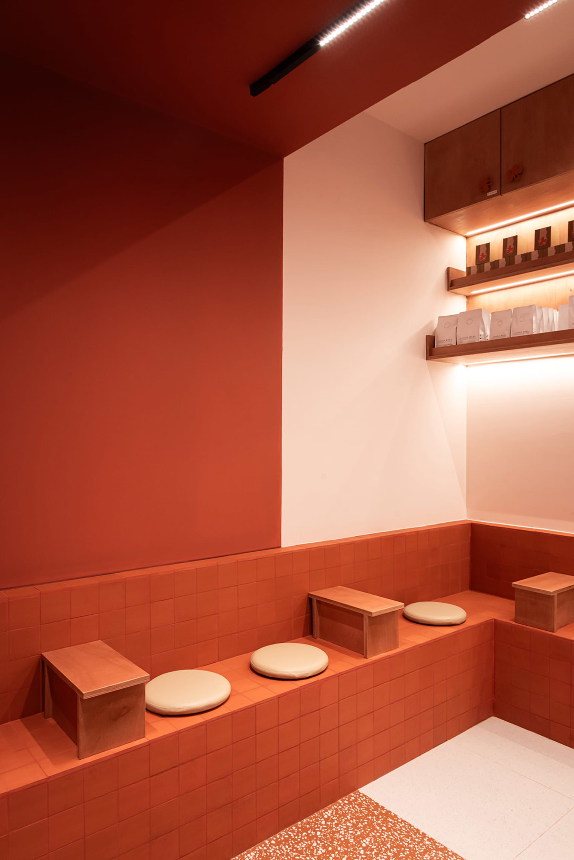 A clean and organized orange painted room with a red accent wall, a bench, stools, and lined up tissue boxes