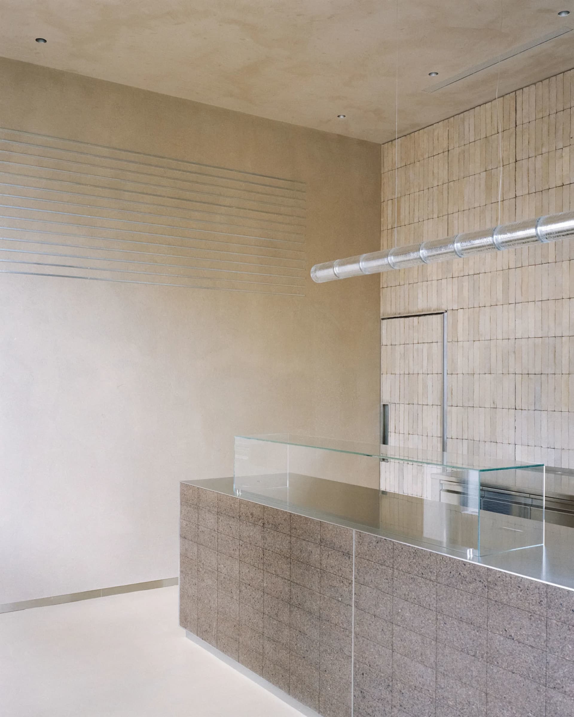 Empty modern kitchen and living area with a glass countertop, cabinets, and a clean minimalistic atmosphere