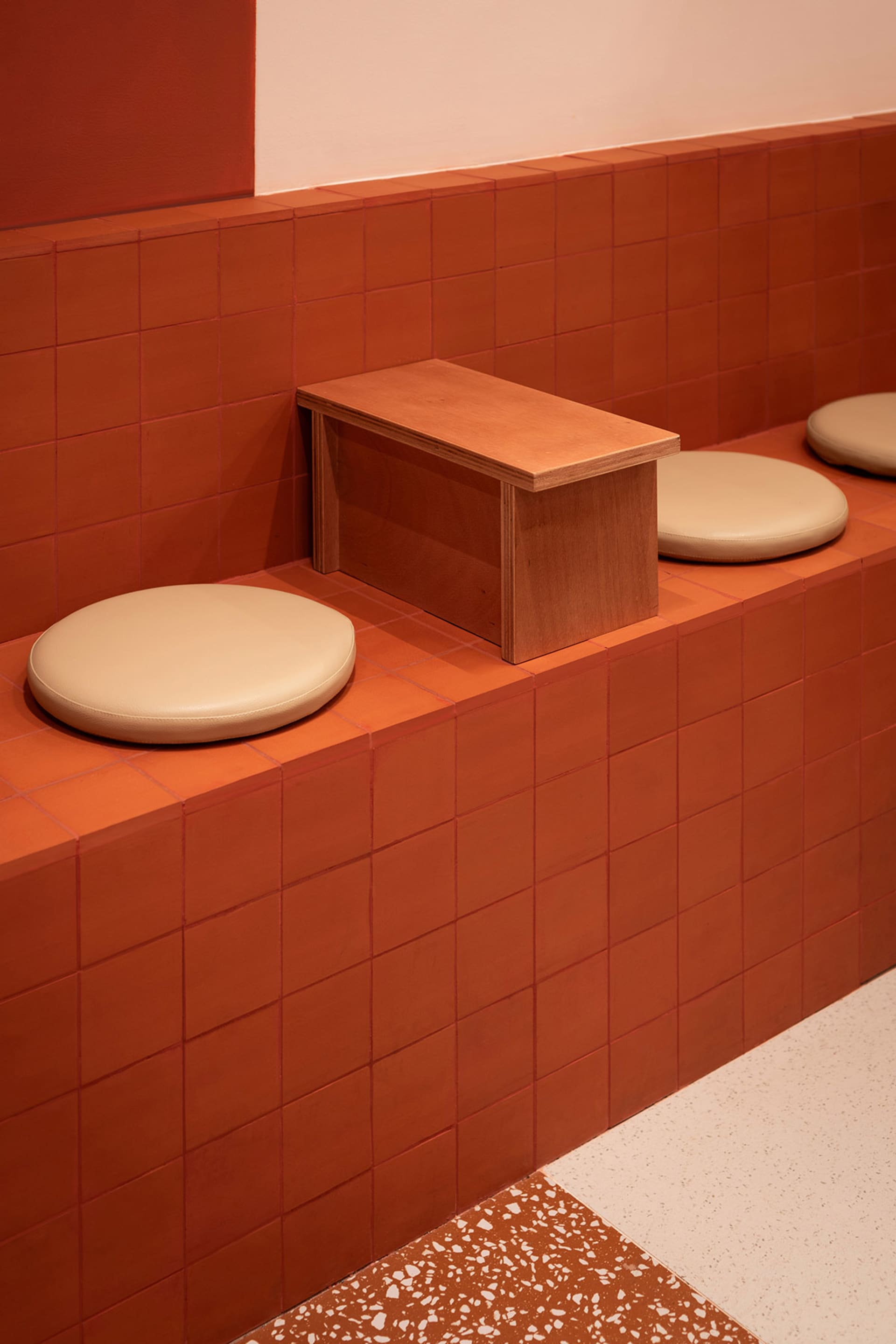 Warm and inviting bathroom with orange tiles, two toilets, and two benches, creating a cozy atmosphere