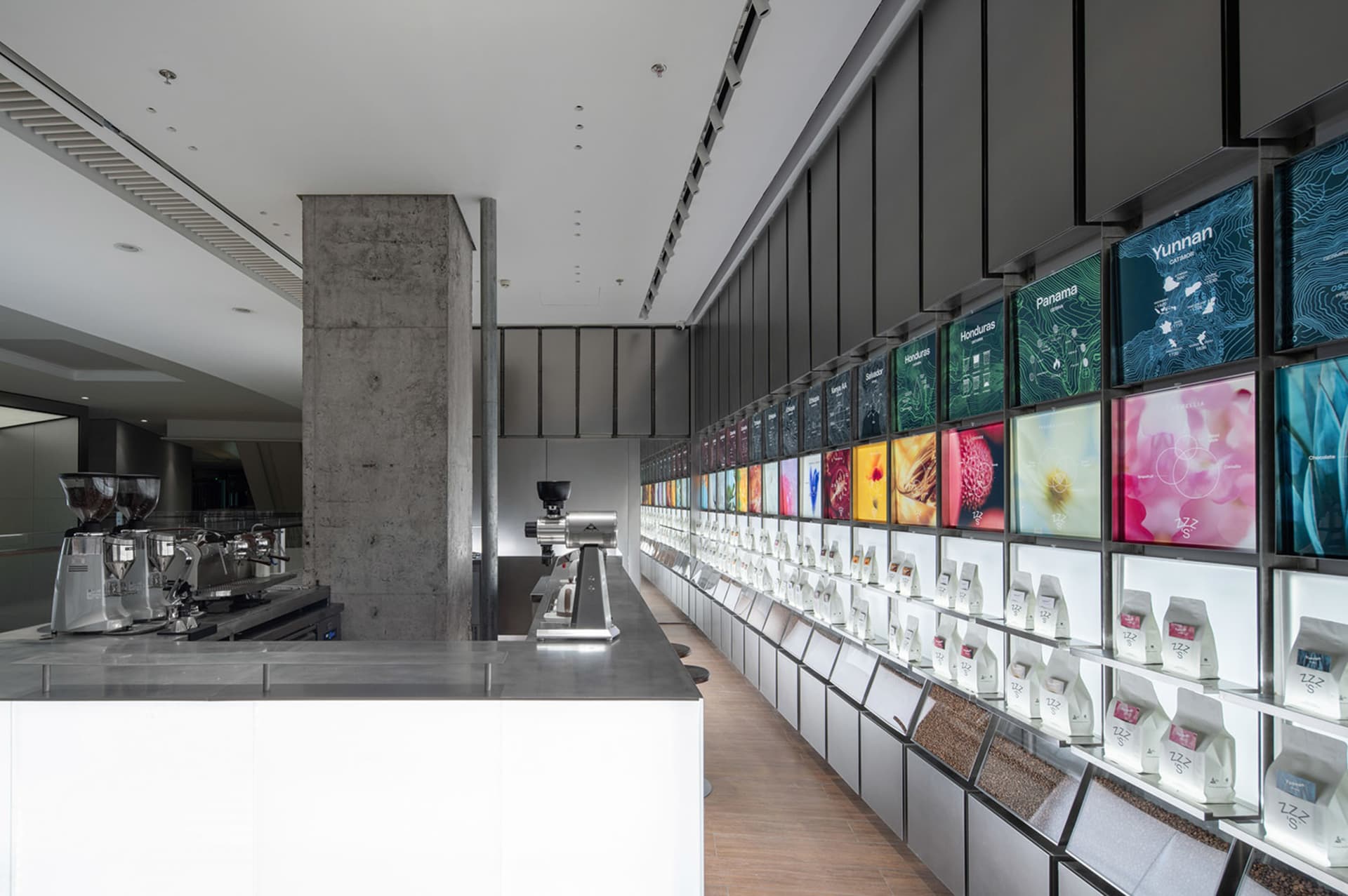 A modern retail space with a long glass countertop displaying various items, flanked by TV screens on the walls, in a clean and organized atmosphere