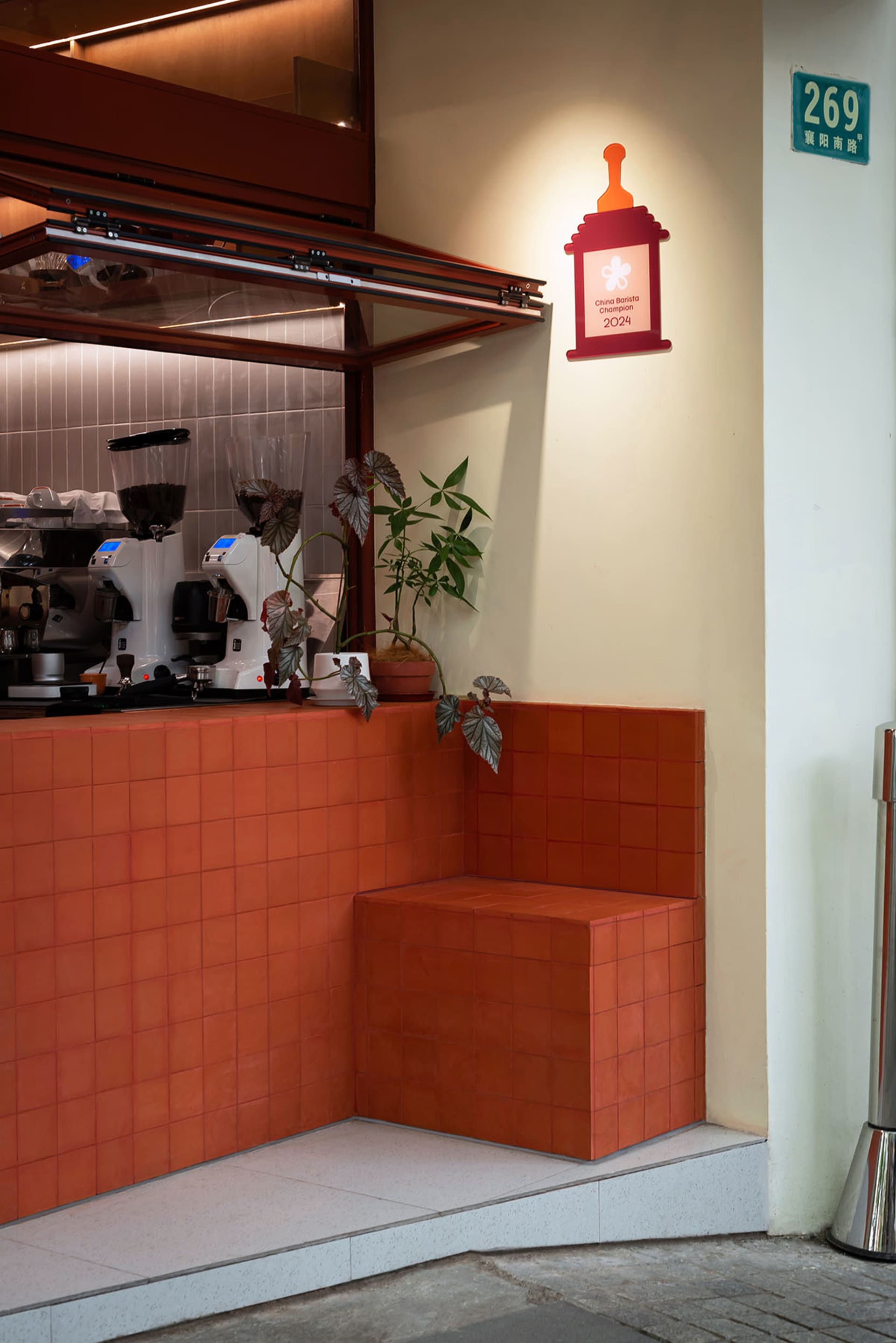 A warm and inviting kitchen with orange tiles, a countertop featuring a coffee maker and sink, and two potted plants