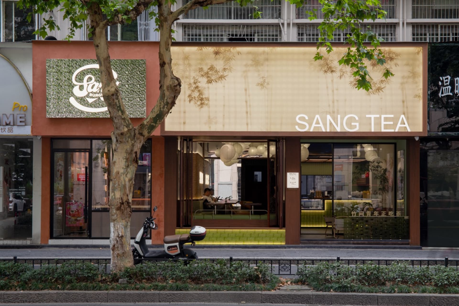 A modern Asian restaurant with orange walls, natural light, and comfortable seating for customers