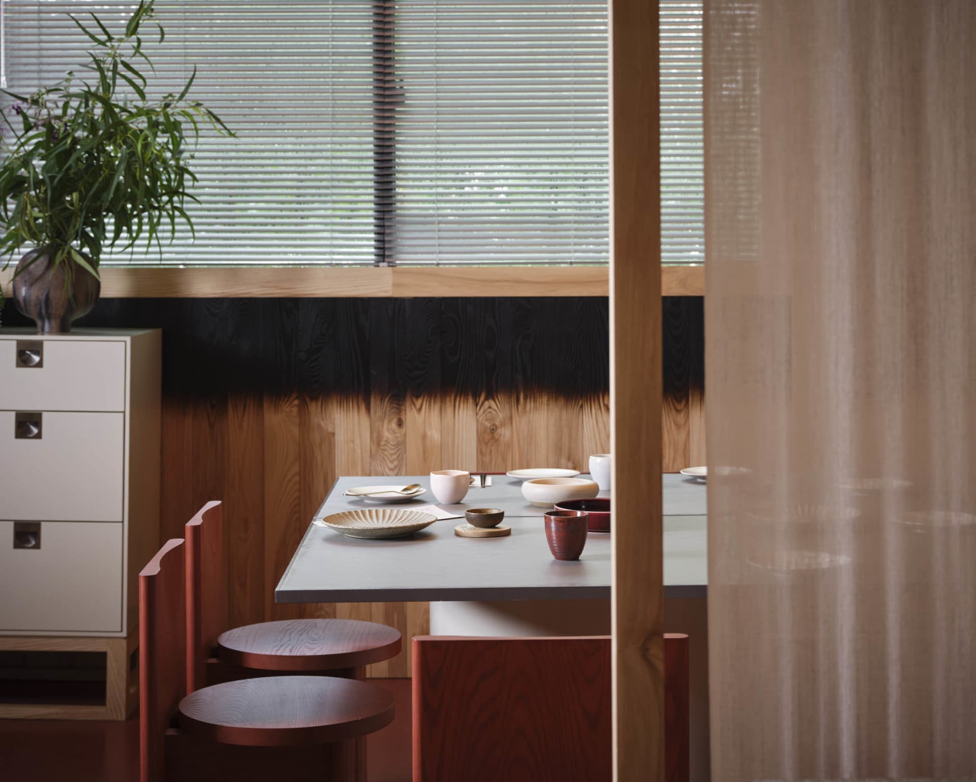 a dining table set with bowls, cups, and spoons in a cozy asian restaurant interior