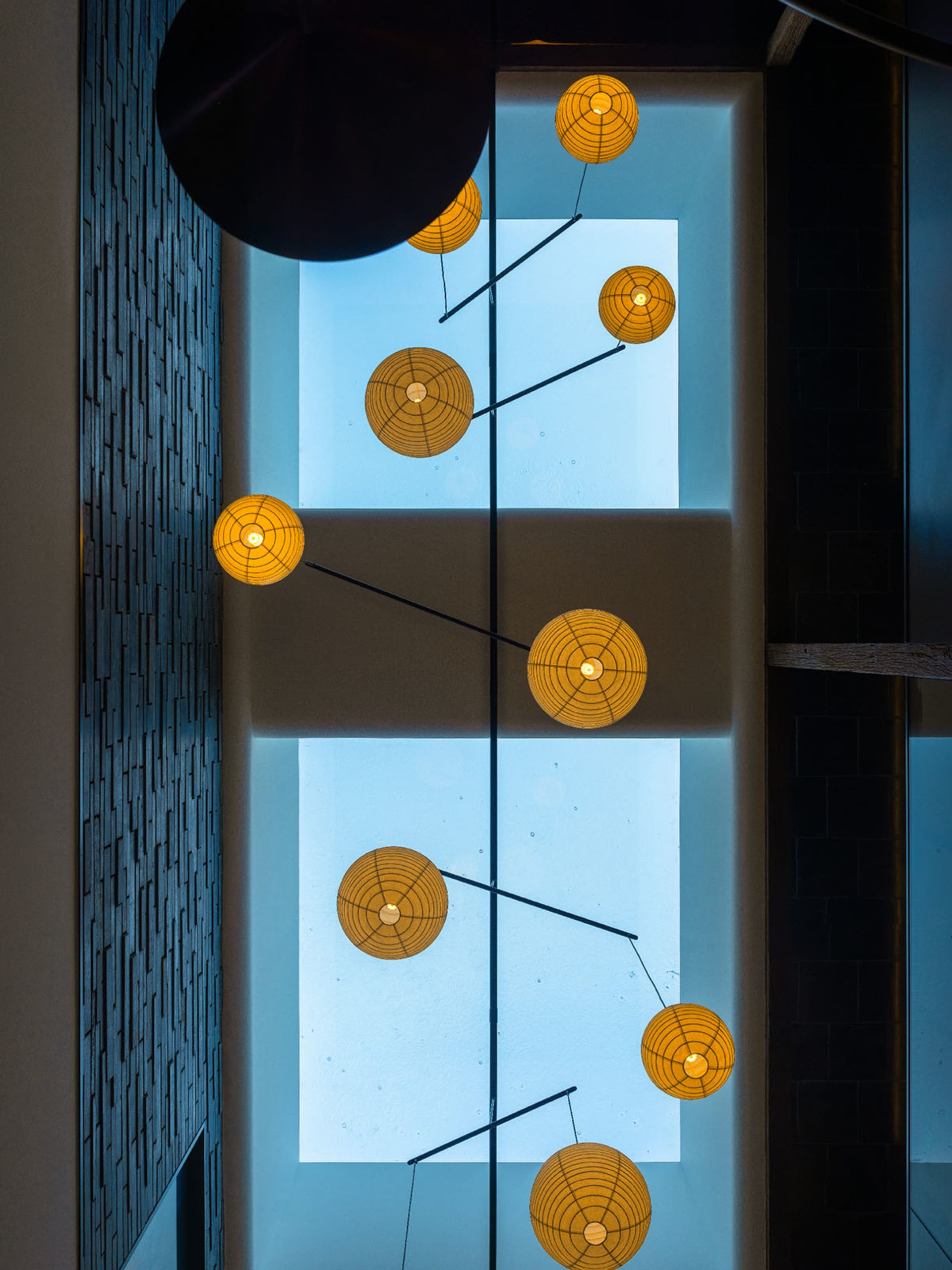 A modern living space with a large window, hanging lights, and a dining table, featuring glass and metal elements
