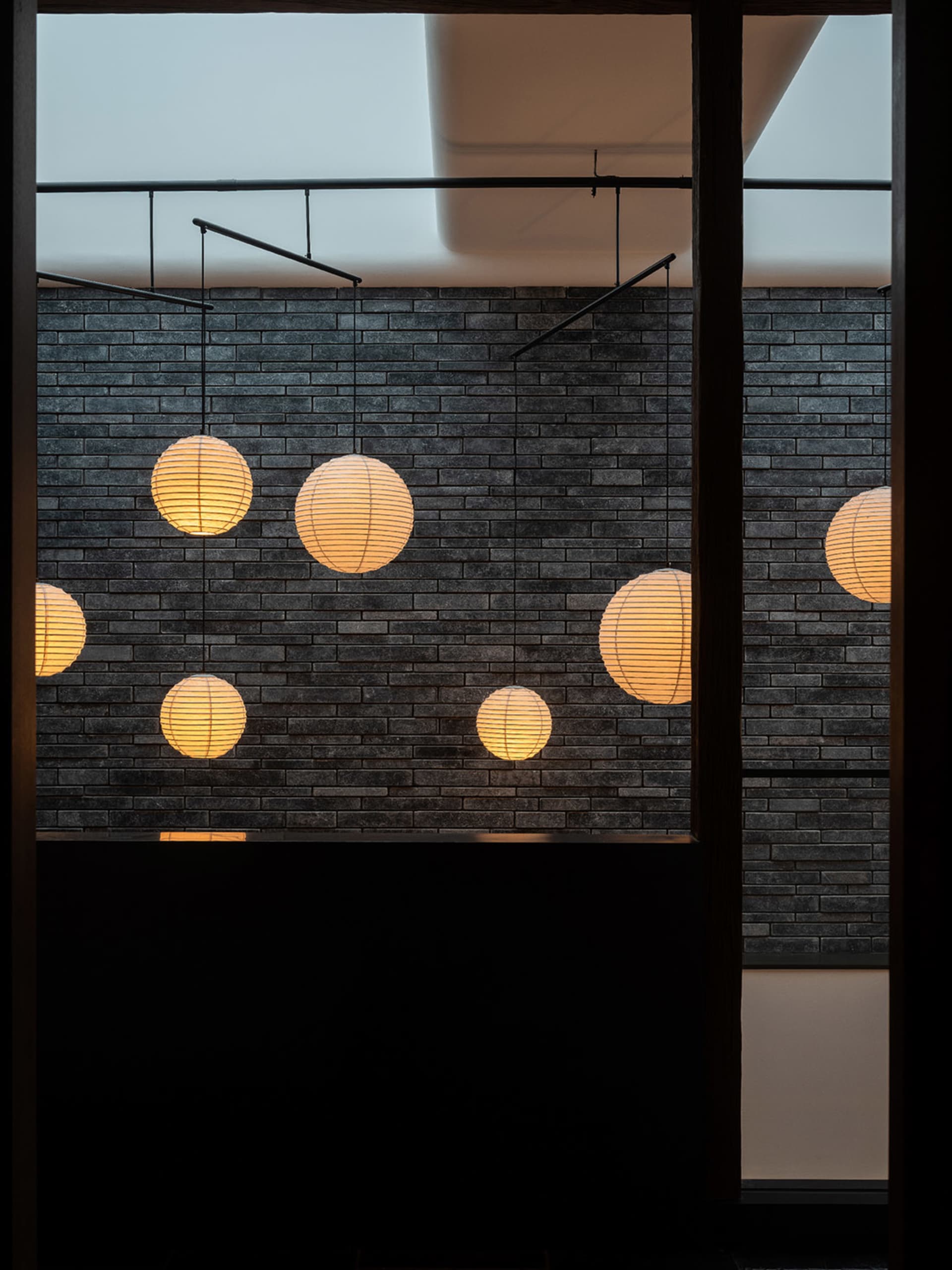 Modern interior design featuring a black brick wall with several lights hanging from it, creating a stylish and modern atmosphere
