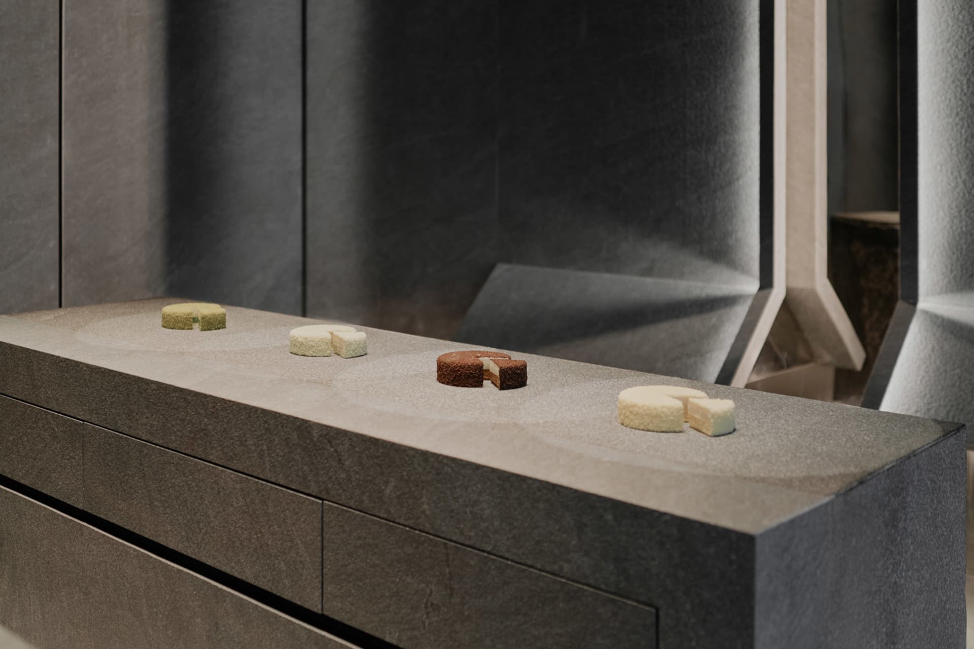 A kitchen countertop made of marble displays four types of cakes in an organized manner, creating a cozy and inviting atmosphere