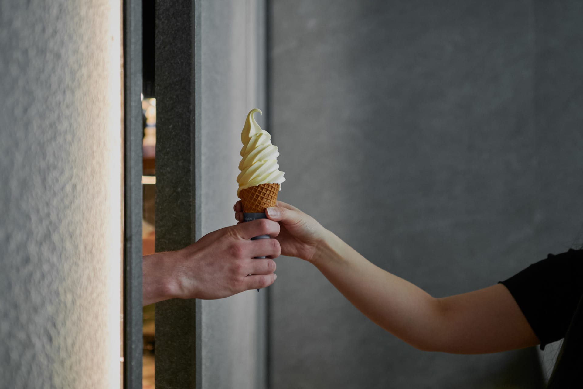 Two people enjoying a yellow ice cream cone together in a casual outdoor setting