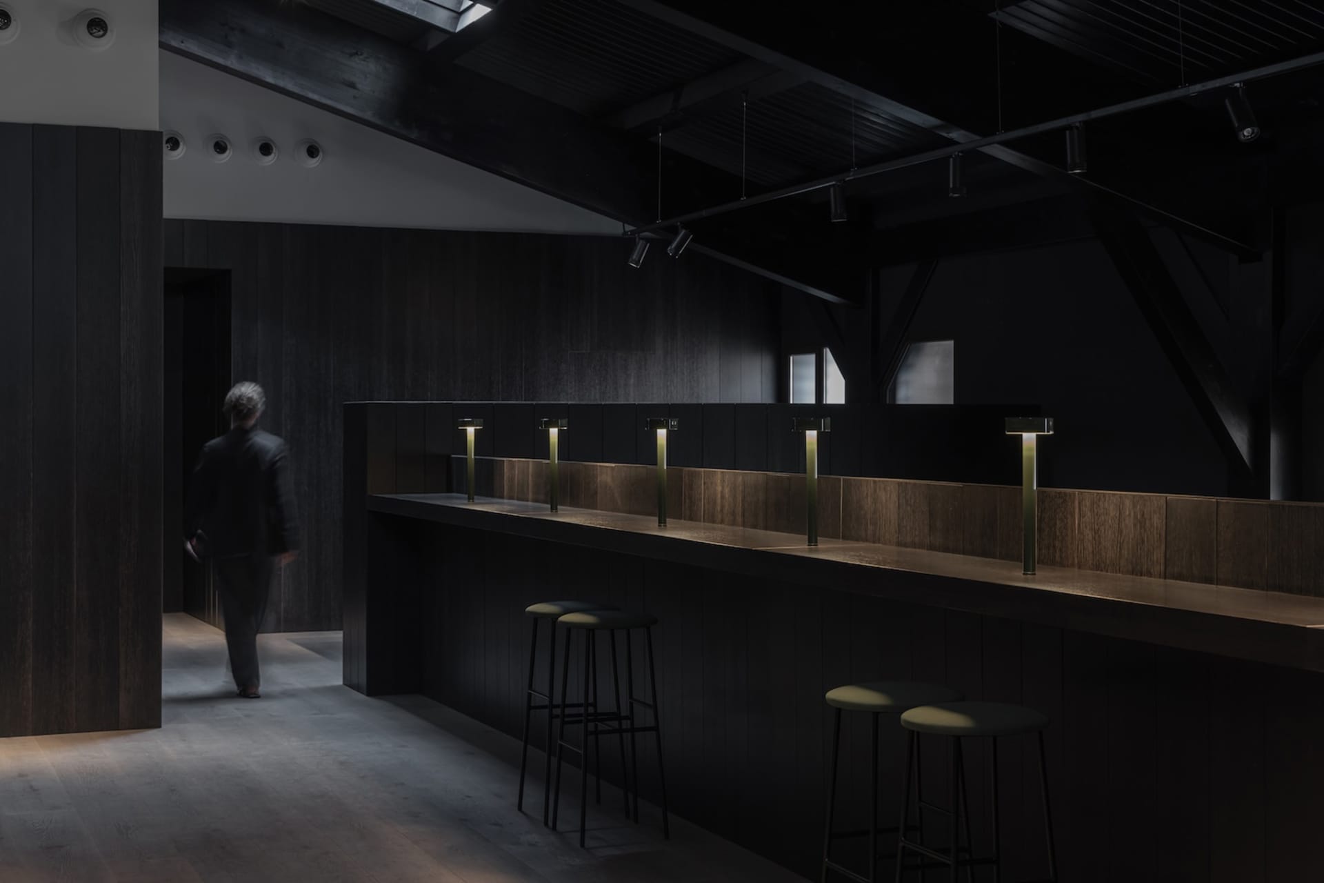 A modern bar area with a well-lit countertop and stools, creating a welcoming atmosphere