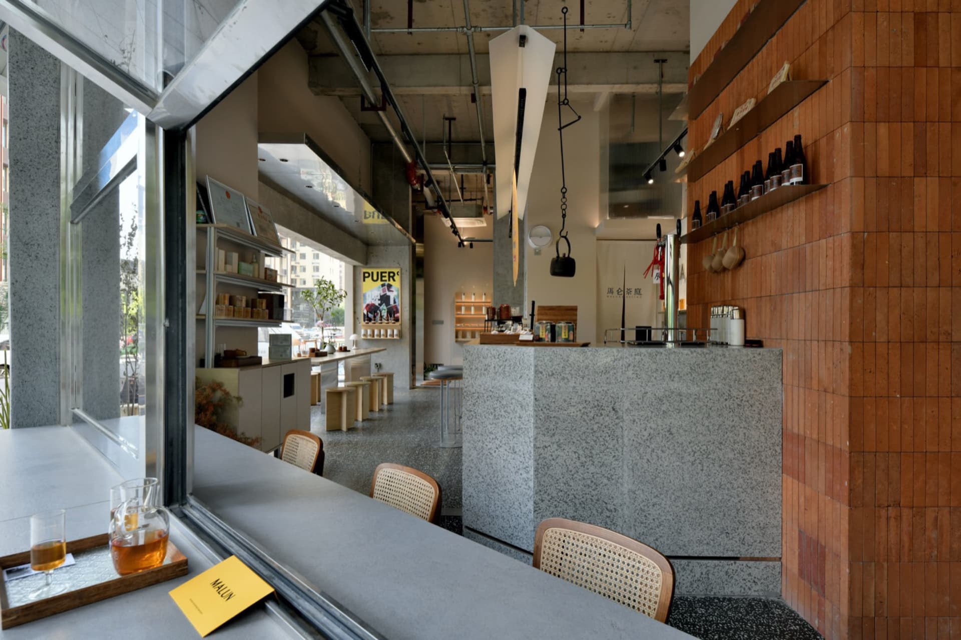 溫馨零售空間，設有木質櫃檯與層架，展示瓶裝飲品與書籍，牆上掛有廣告與招牌，並有多張顧客座椅