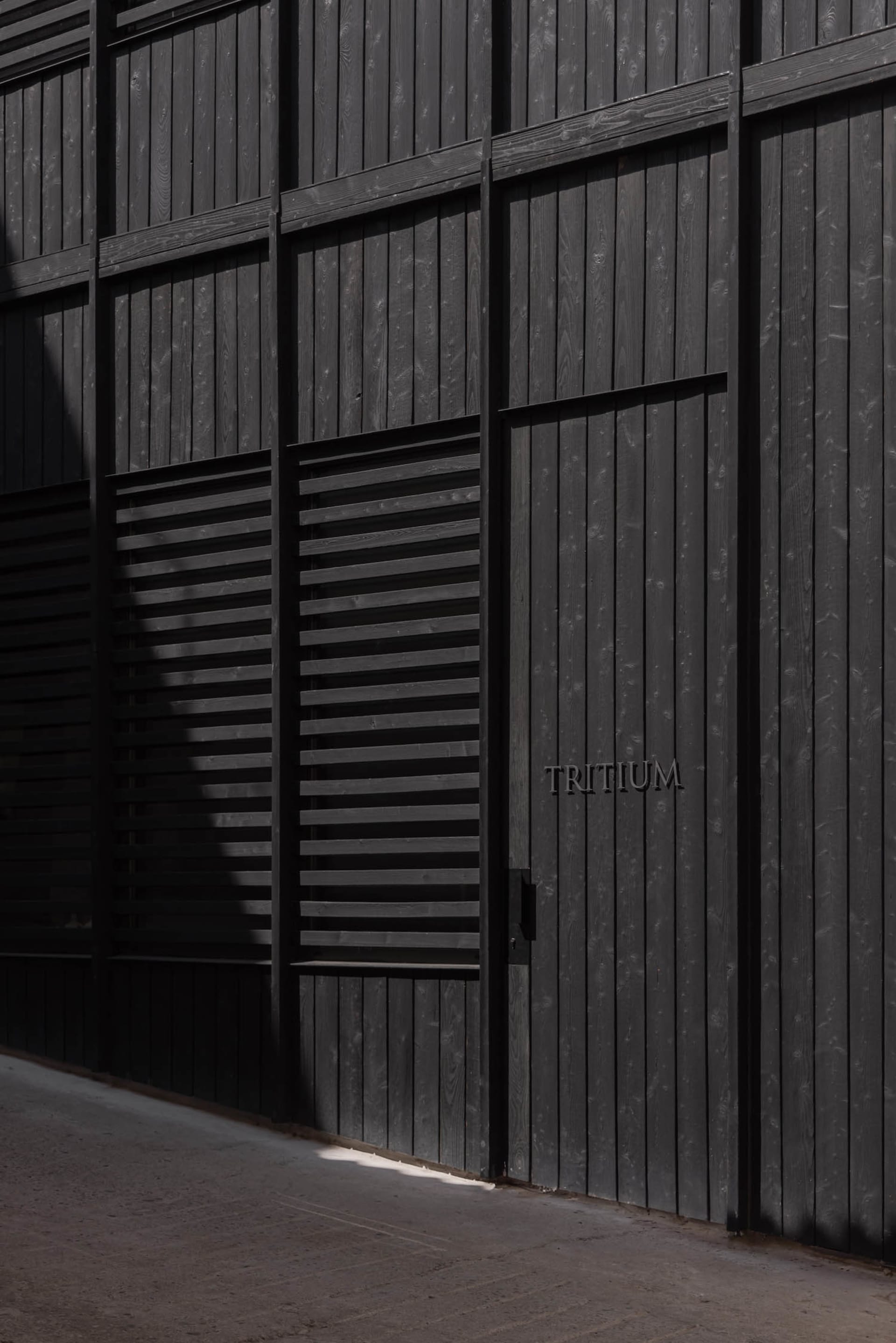 A dark and mysterious exterior building facade with a black door and a white sign, set against a dimly lit background