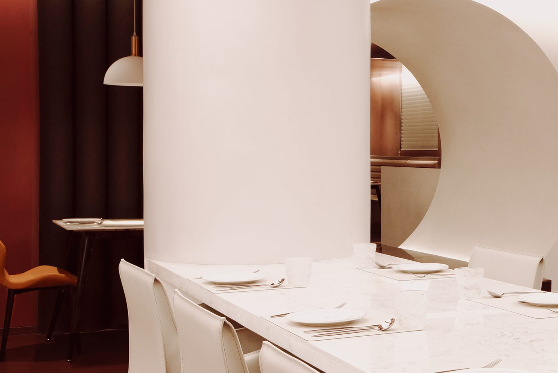 A dining area in a restaurant with a white table set with fine china, wine glasses, and various tableware, creating a sophisticated atmosphere
