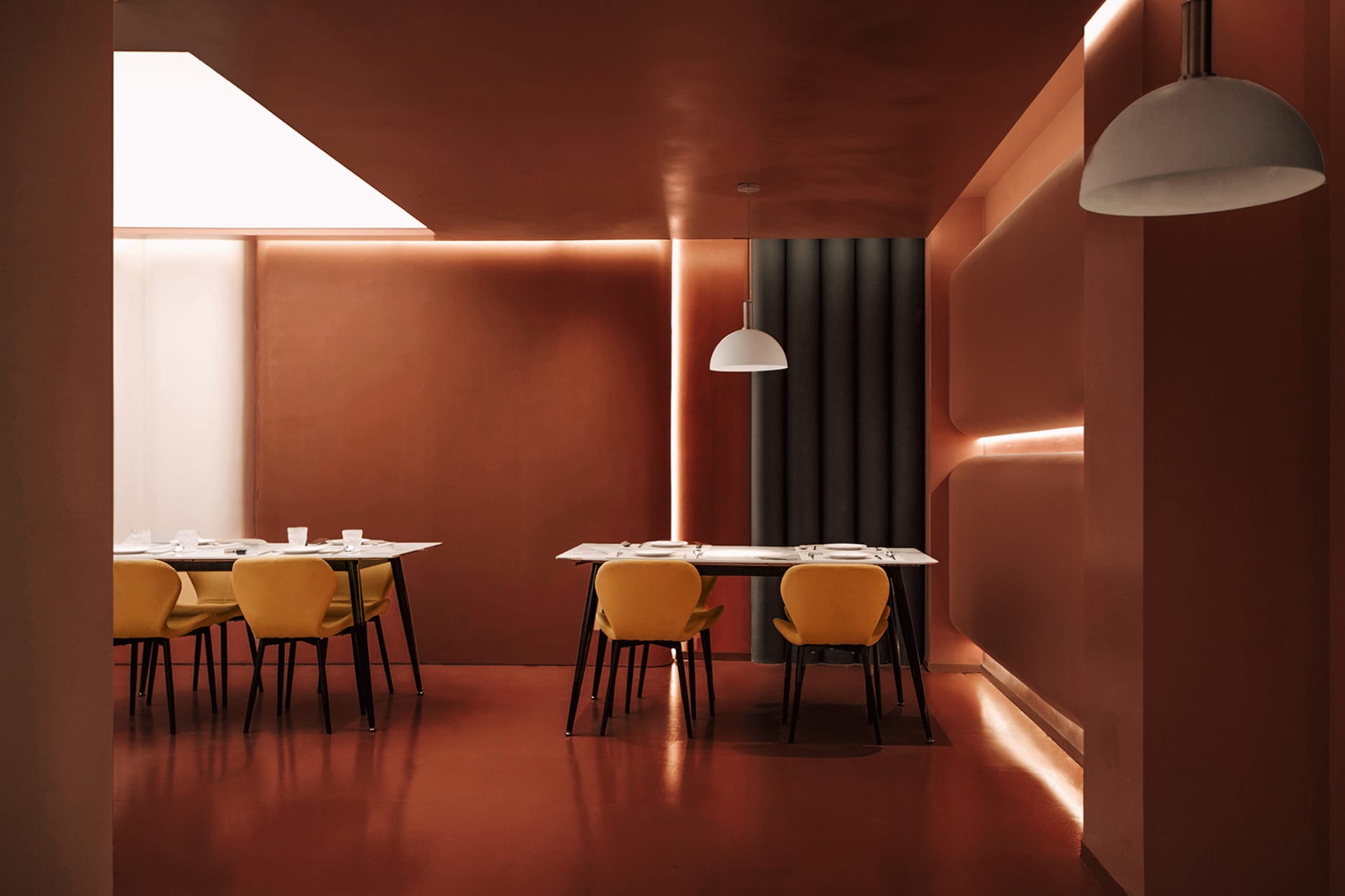 A restaurant with two dining tables, red walls, and wooden flooring, creating a warm and inviting atmosphere
