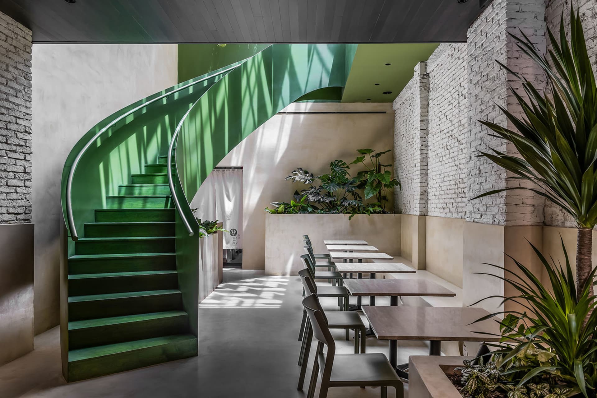 Elegant dining area with a spiral staircase, multiple chairs, and dining tables arranged throughout the space