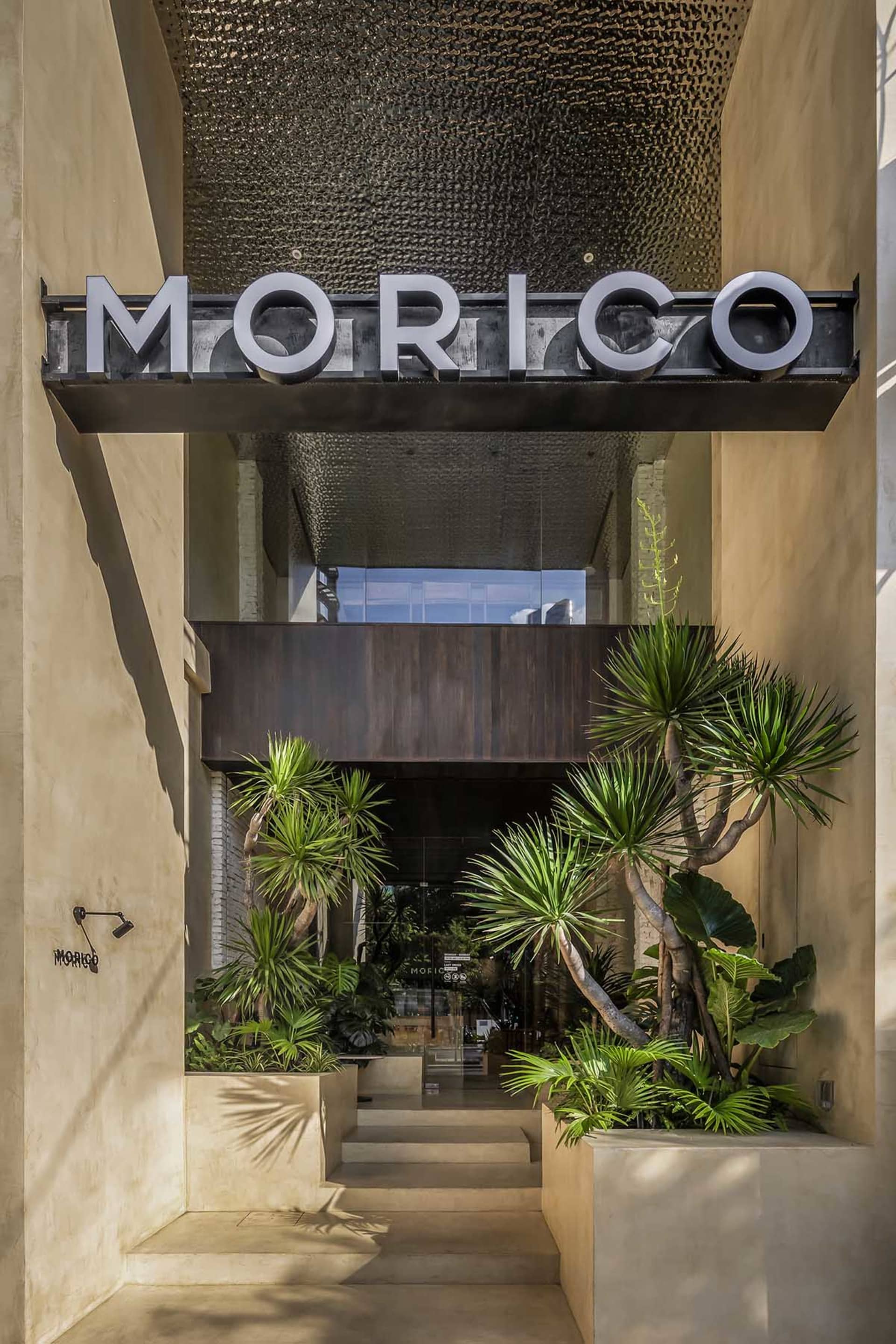 一個溫馨的入口處，設有大型「Morico」招牌，周圍環繞盆栽植物與茂密綠意