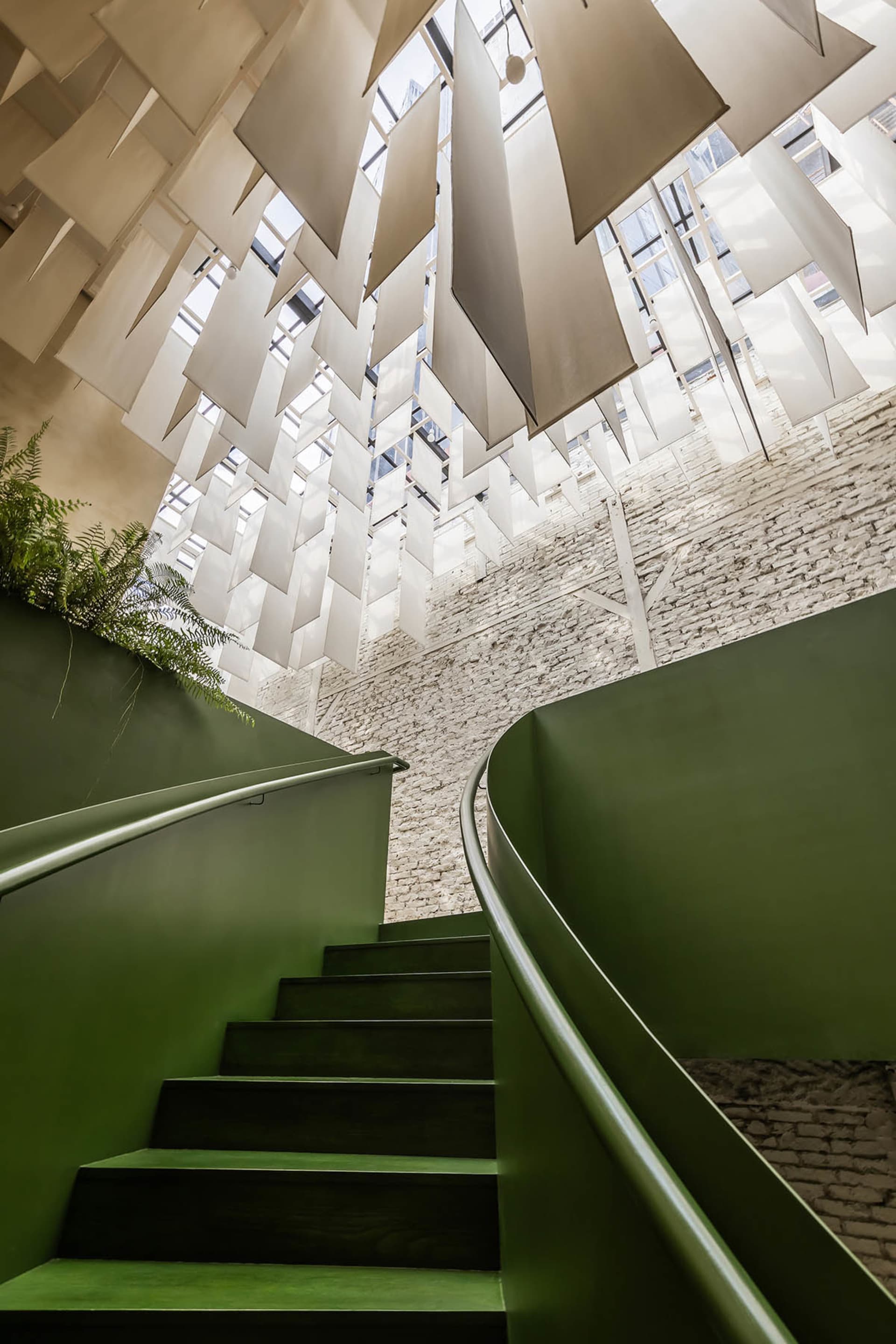 A classic staircase with stone steps in a building with white walls and a green tinted stairwell, exuding a sense of history and calmness