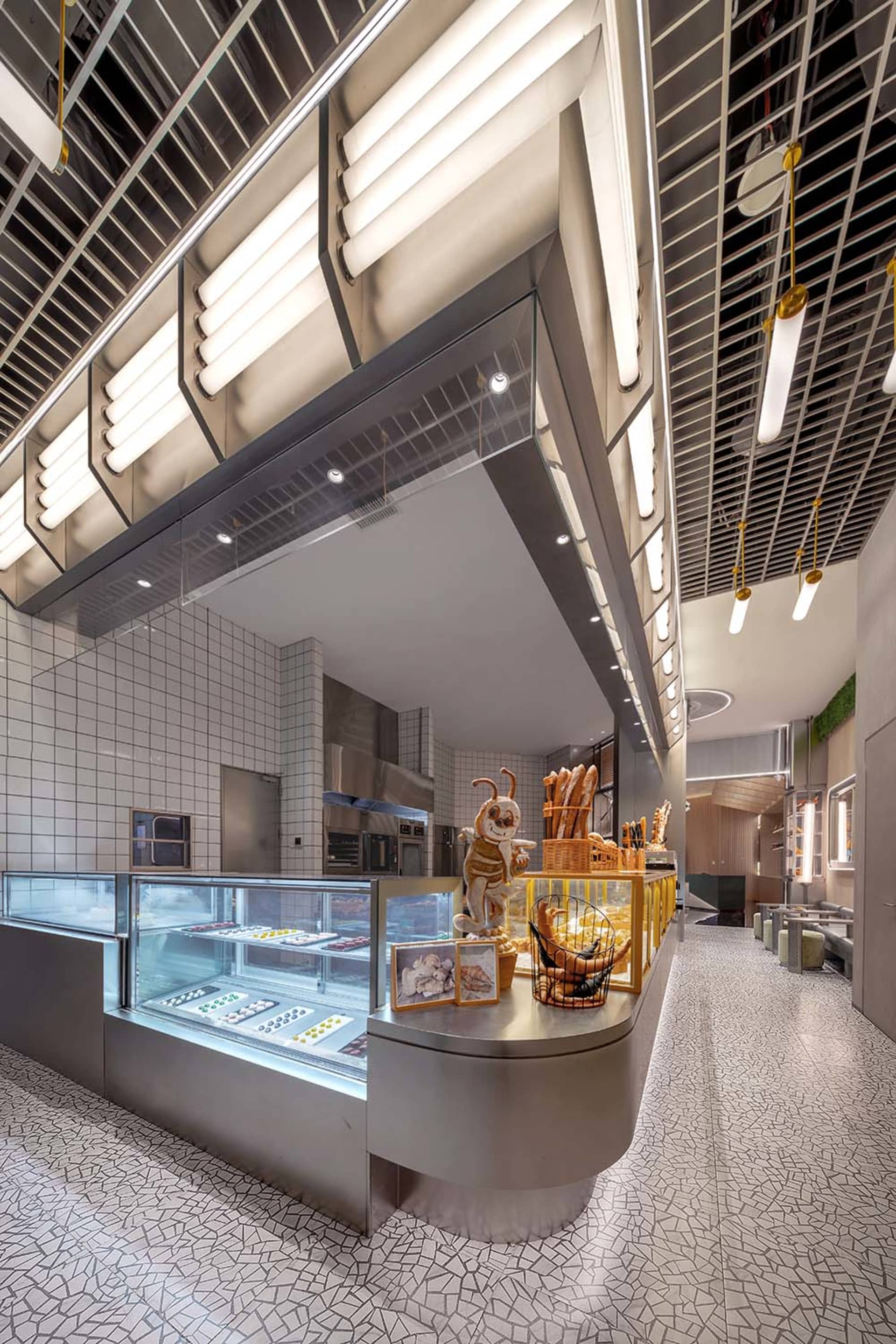A modern restaurant interior with a kitchen area and dining space, featuring a large window, clean lines, and minimal decoration