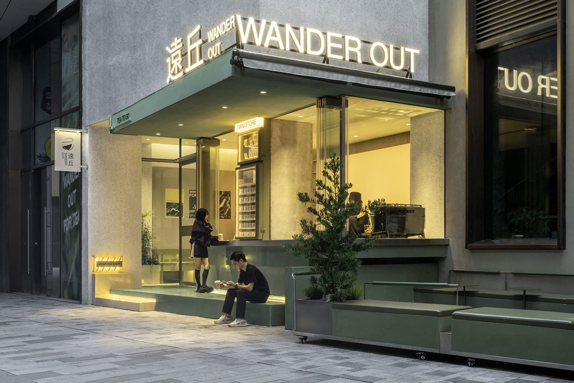 Modern Asian restaurant with green walls, glass front, and outdoor seating area with potted plants and a chair