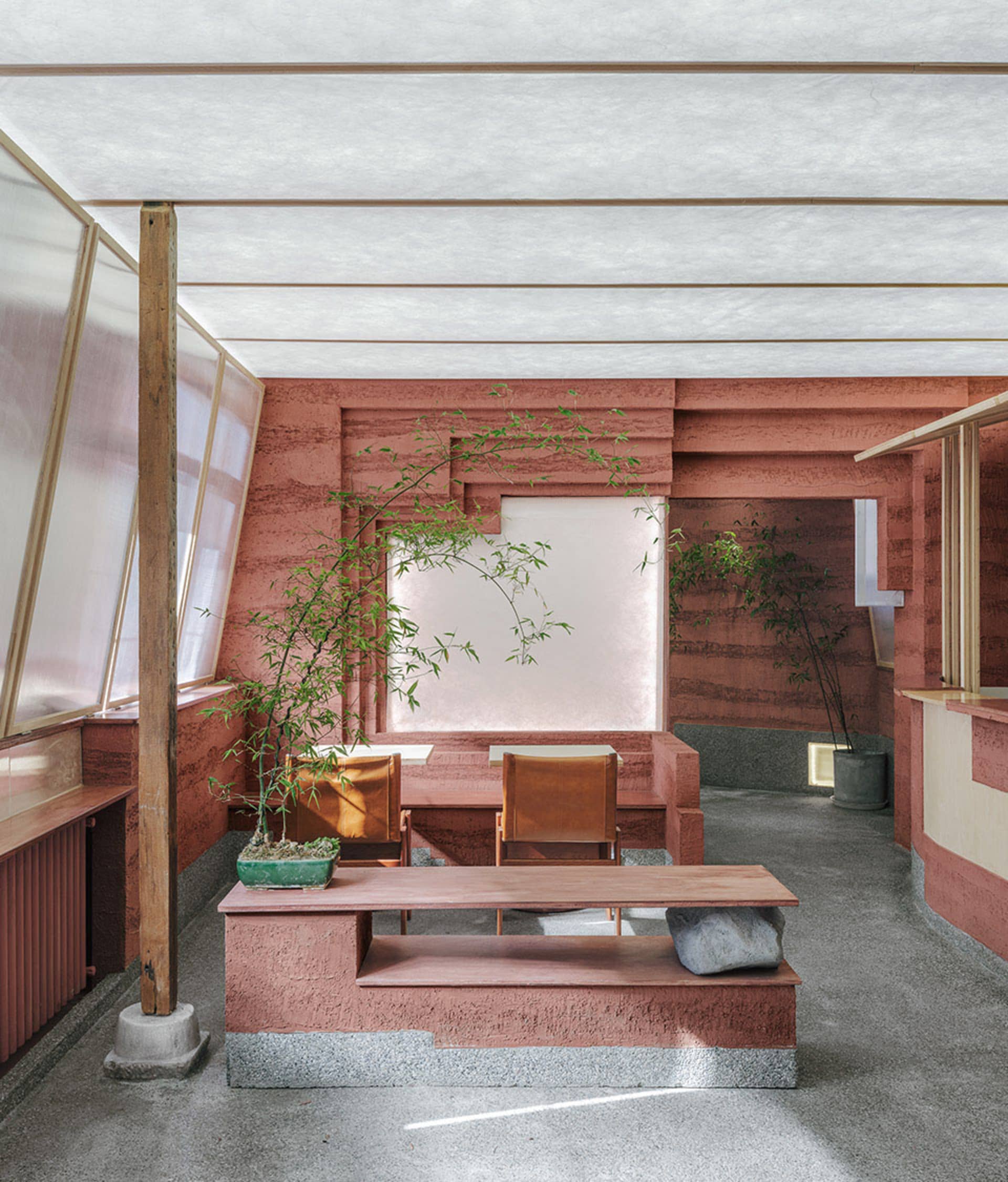Open modern living area with a red interior design theme, featuring two couches, a dining table, chairs, and a potted plant, with a focus on comfort and functionality