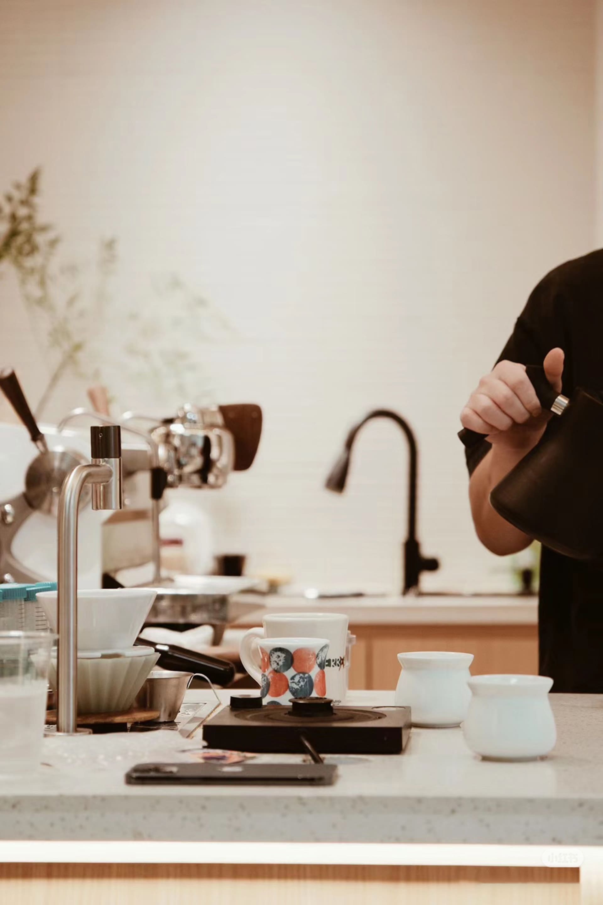 A casual kitchen with a focus on functionality, featuring a wood and metal construction, with appliances, cups, and utensils on the countertop