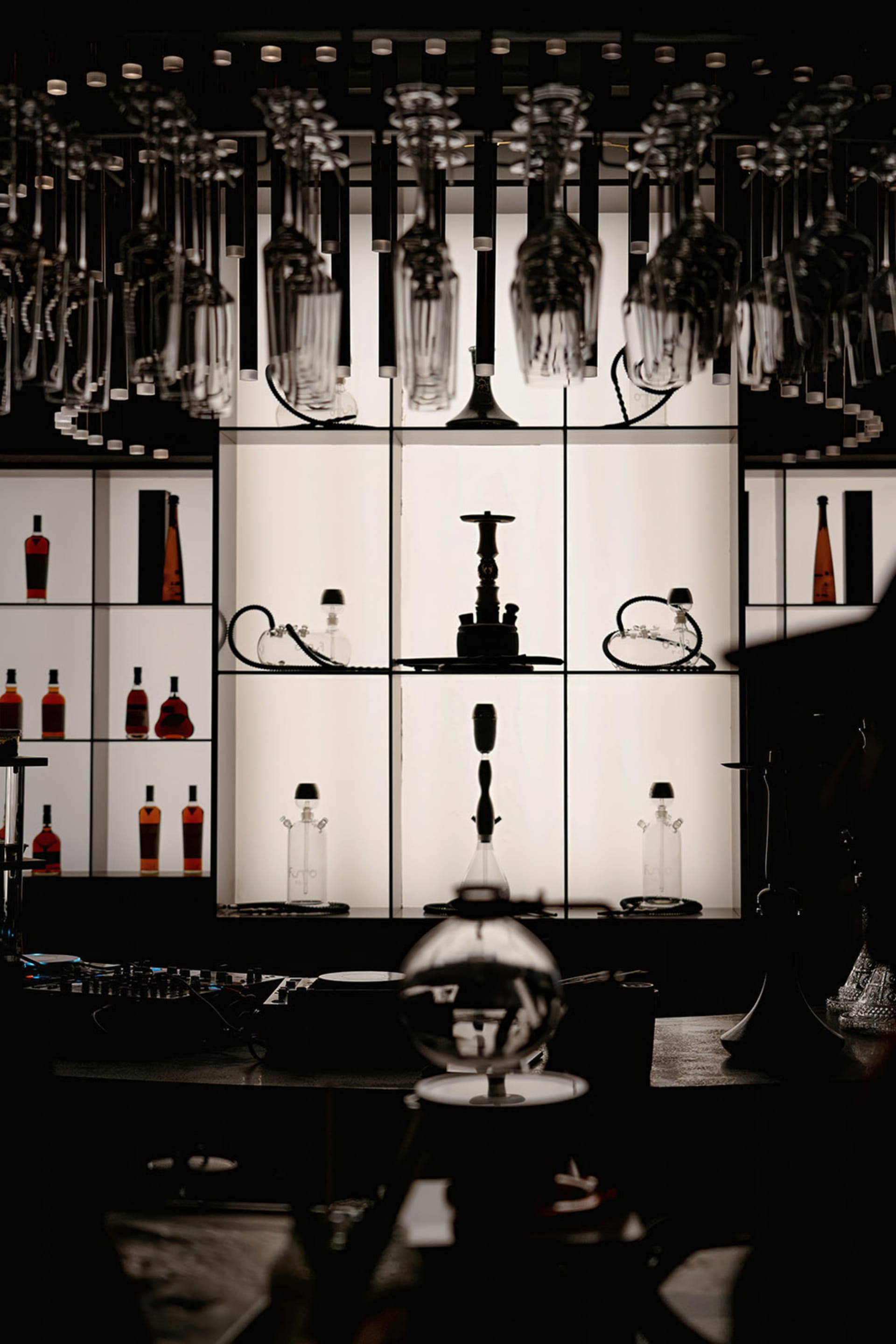 A cozy bar area with a collection of liquor bottles on various surfaces, including distressed wood and glass, in a warm and inviting atmosphere