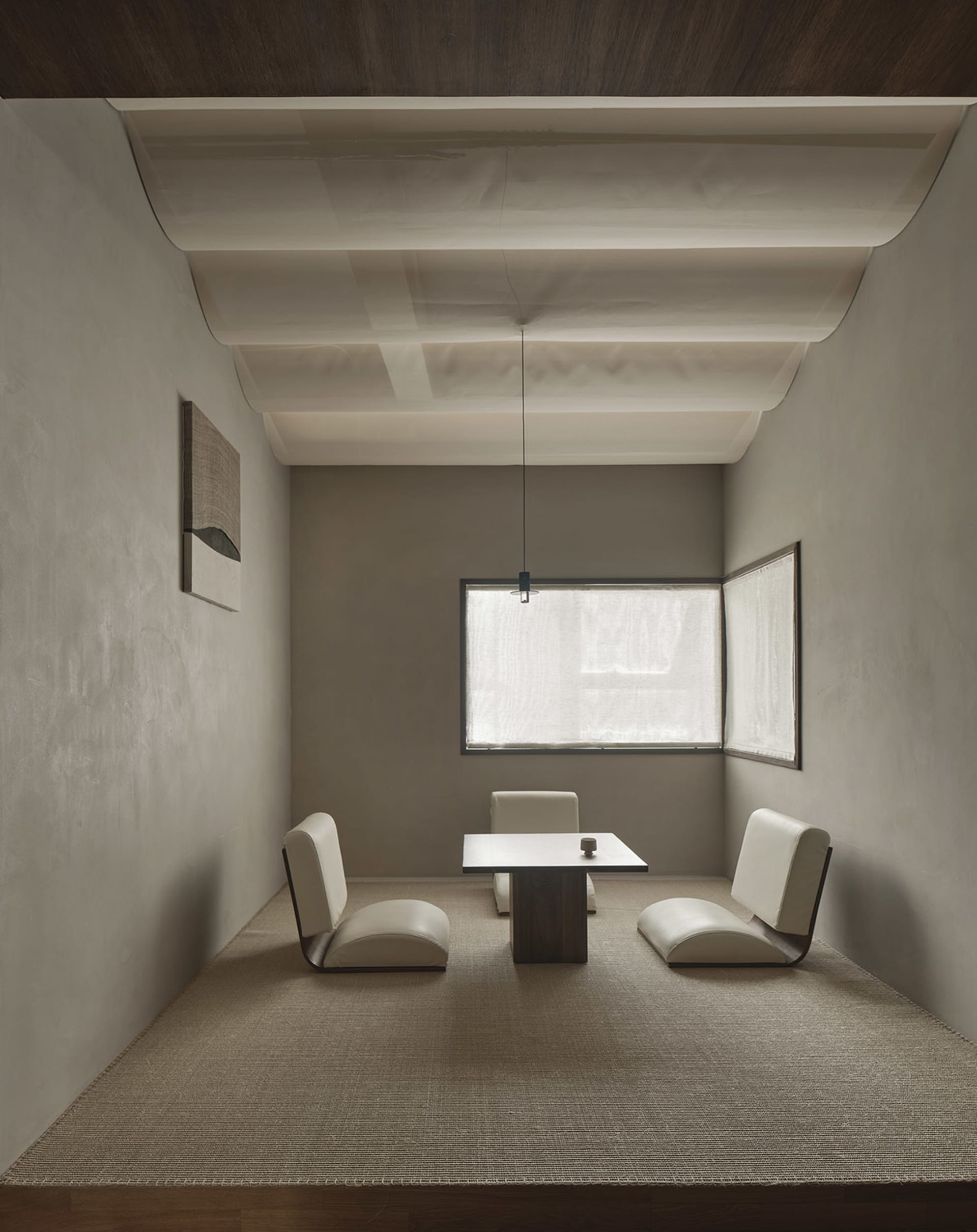 Dimly lit living area with a dining table and chairs, minimalistic design, and a cozy seating arrangement