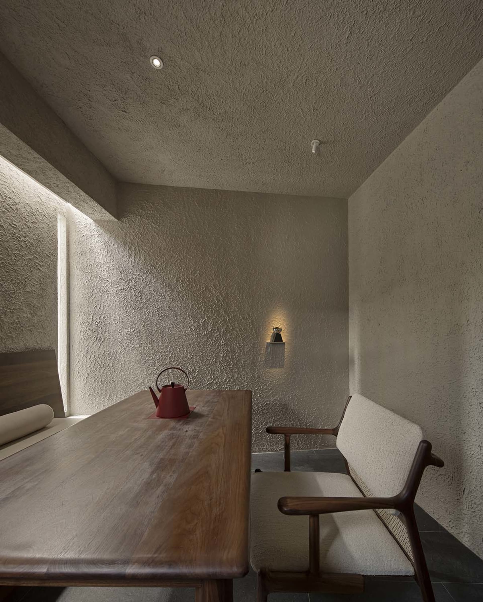 燈光柔和的客廳空間，配有餐桌、椅子與水泥磚牆，營造舒適現代氛圍