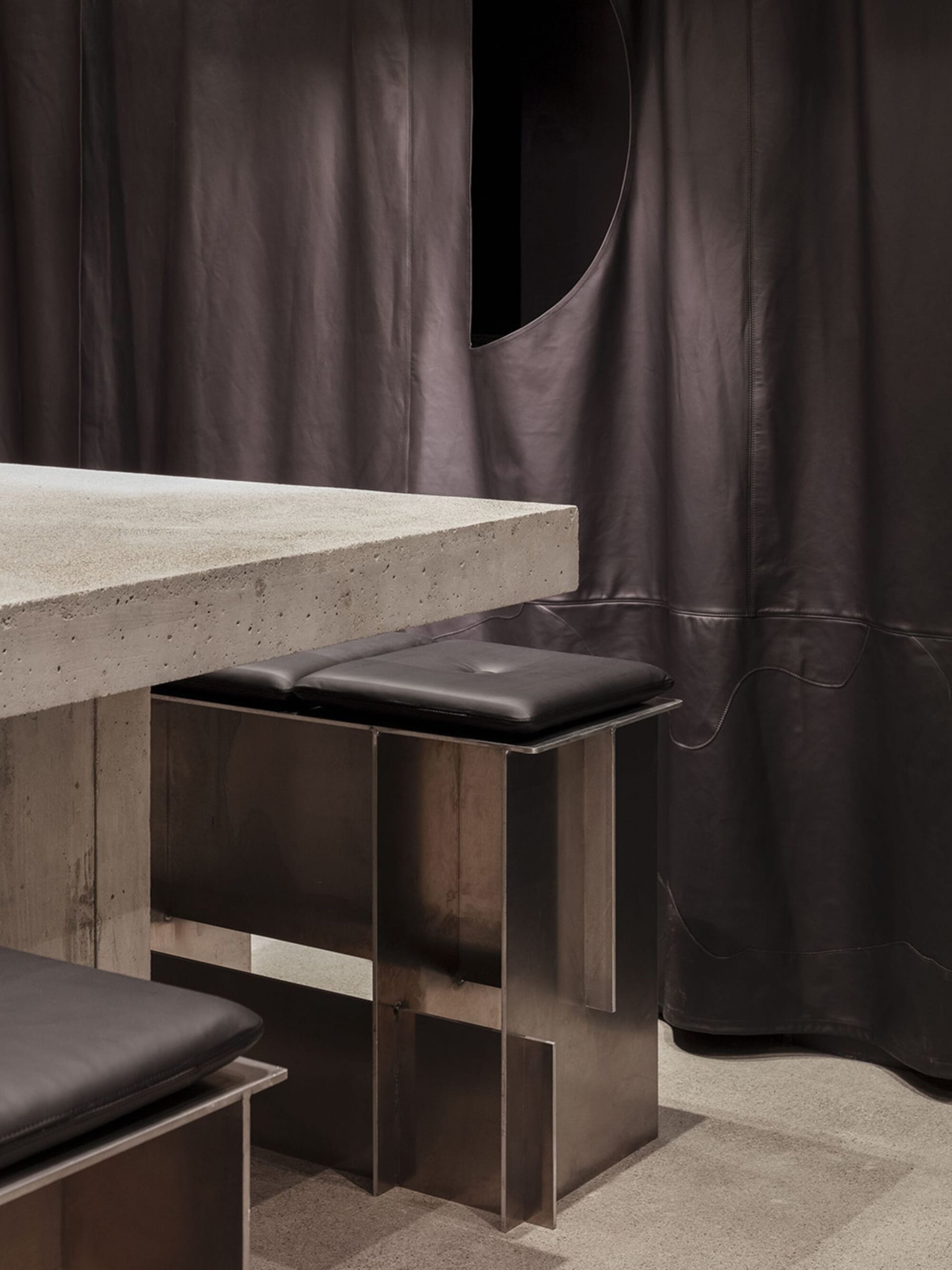 Dining table with two chairs on each side, surrounded by a modern and industrial atmosphere with a concrete table and stylish living space